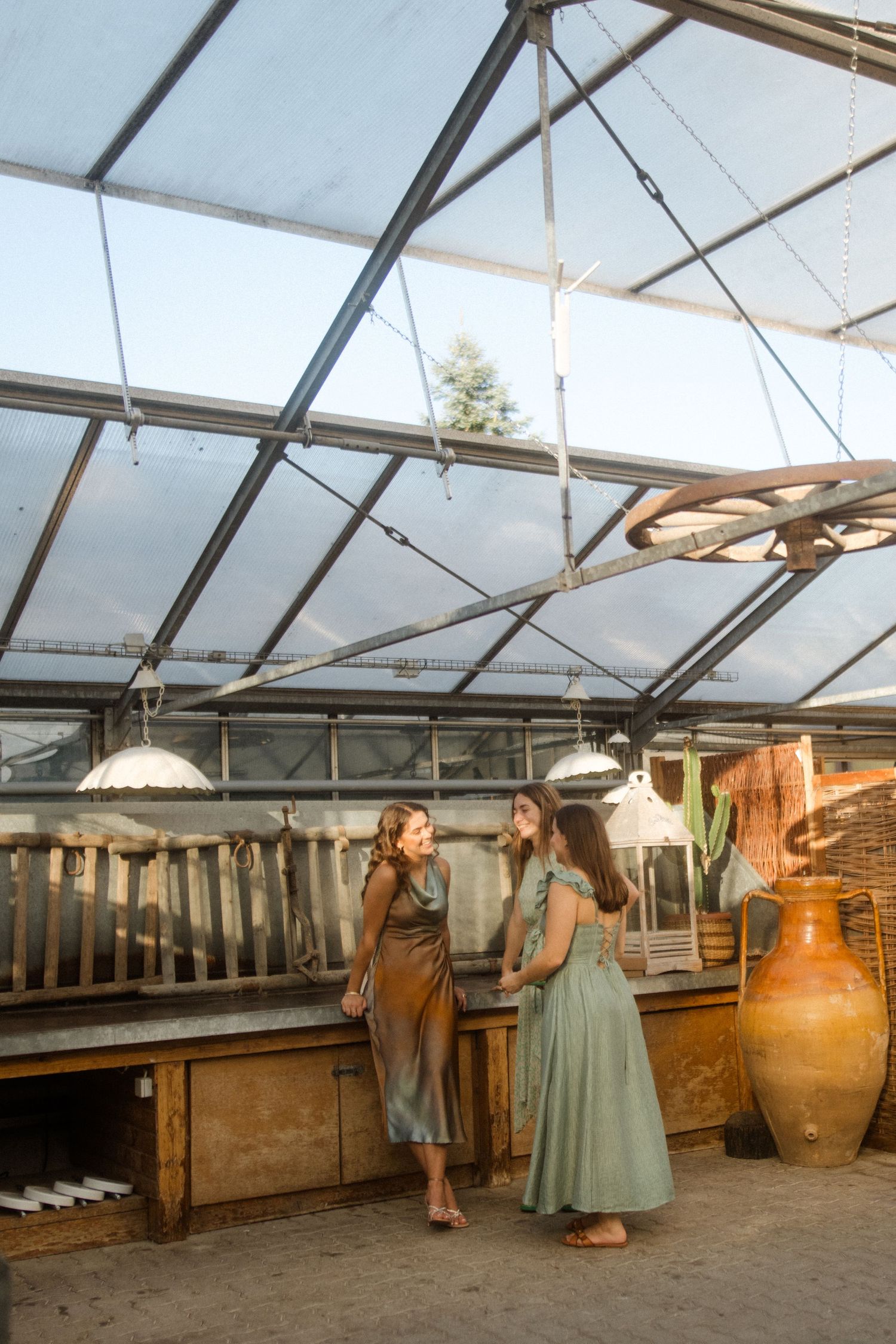 Two guests chatting in a greenhouse-style venue with hanging lights and rustic decor.