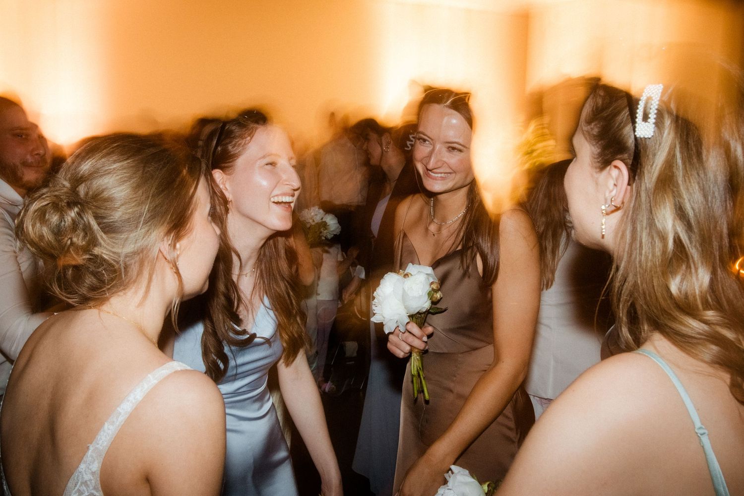 Bridesmaids share a joyful candid moment at a wedding celebration.