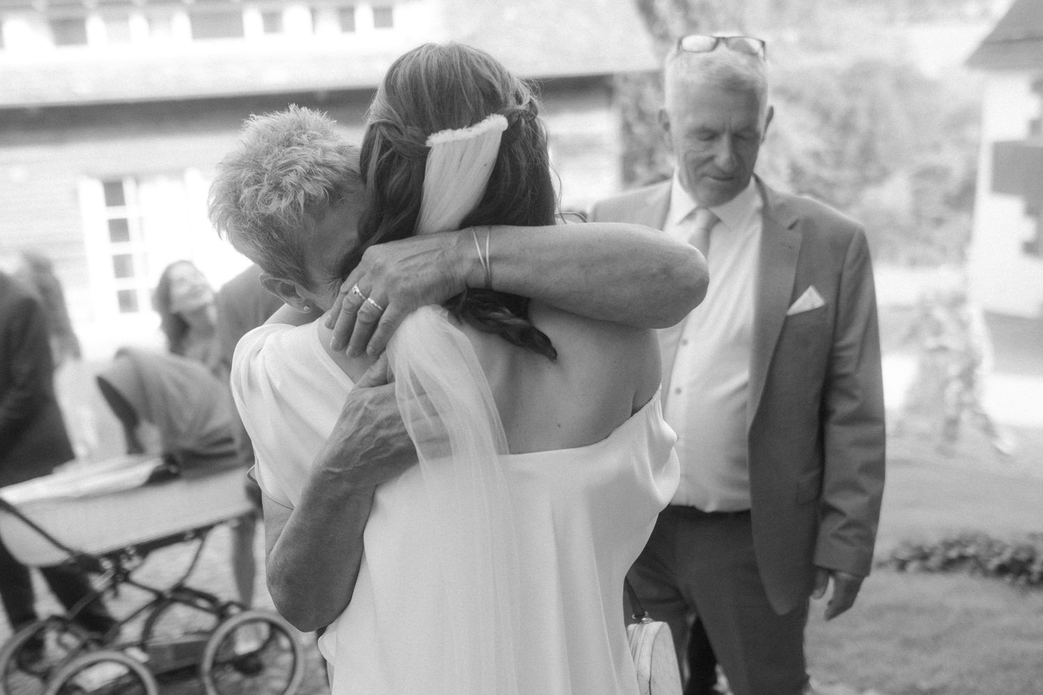 A tender embrace at an outdoor wedding celebration captured in black and white photography.