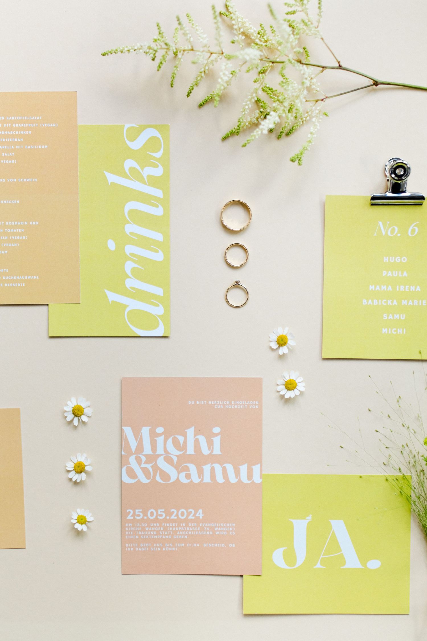 Wedding stationery in lime green and peach tones with gold rings and small daisies.