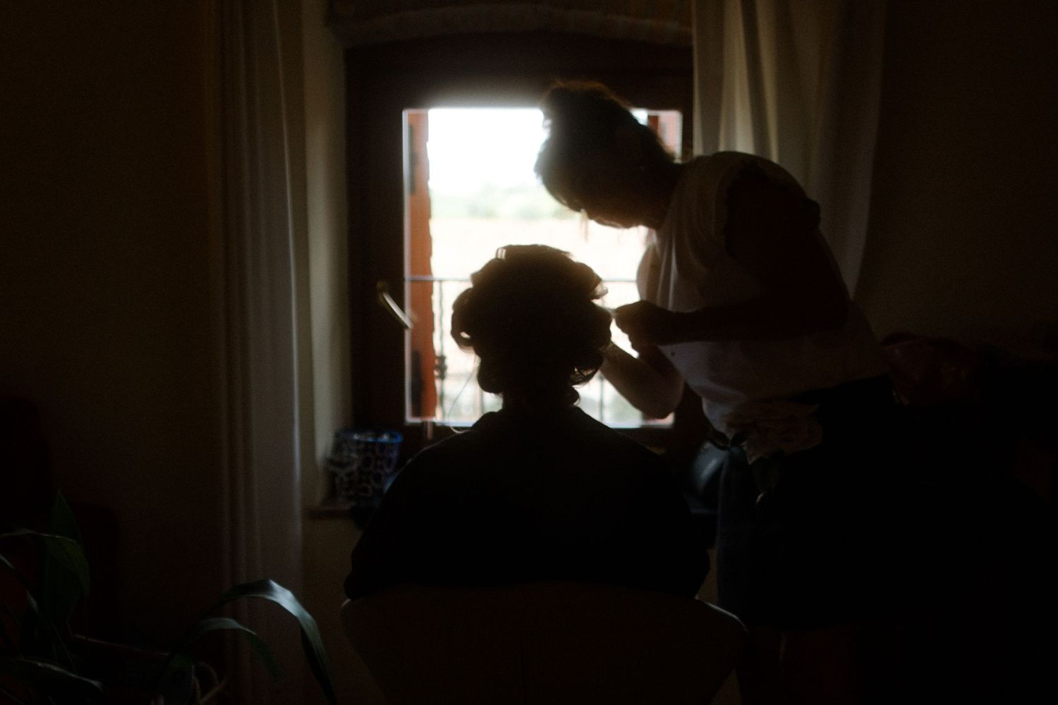 Silhouette of wedding preparation by a window.