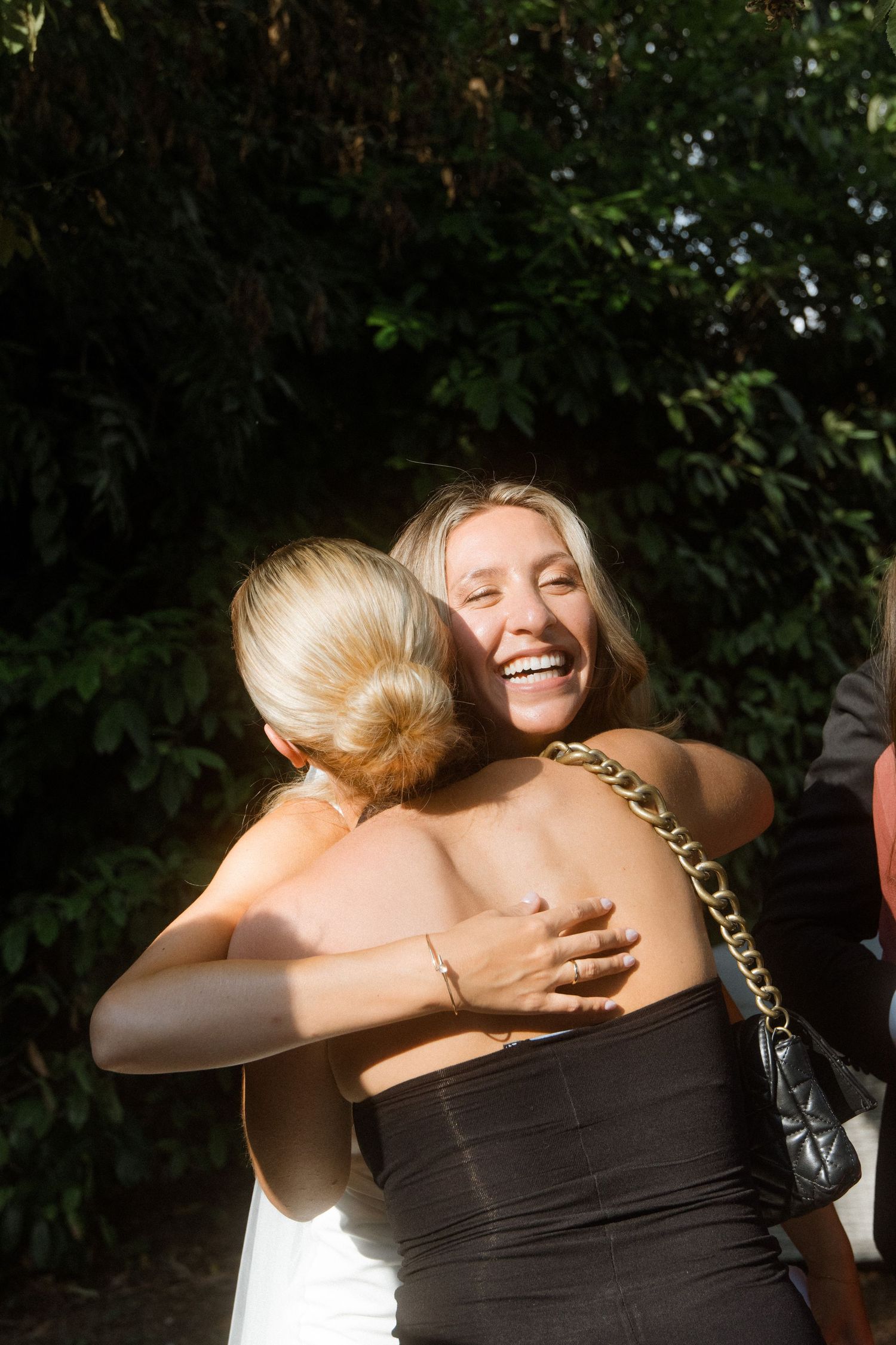 Warm embraces exchanged during sunny outdoor celebration.