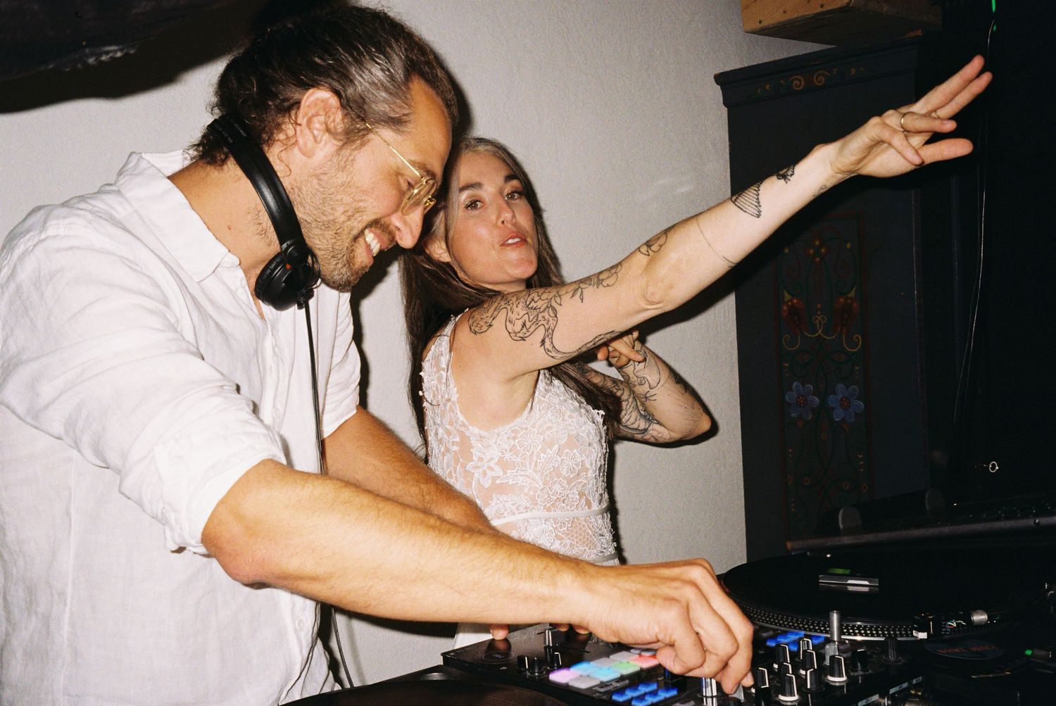 DJs perform at a nightclub mixing music on turntables in a dark atmosphere with flashing lights.