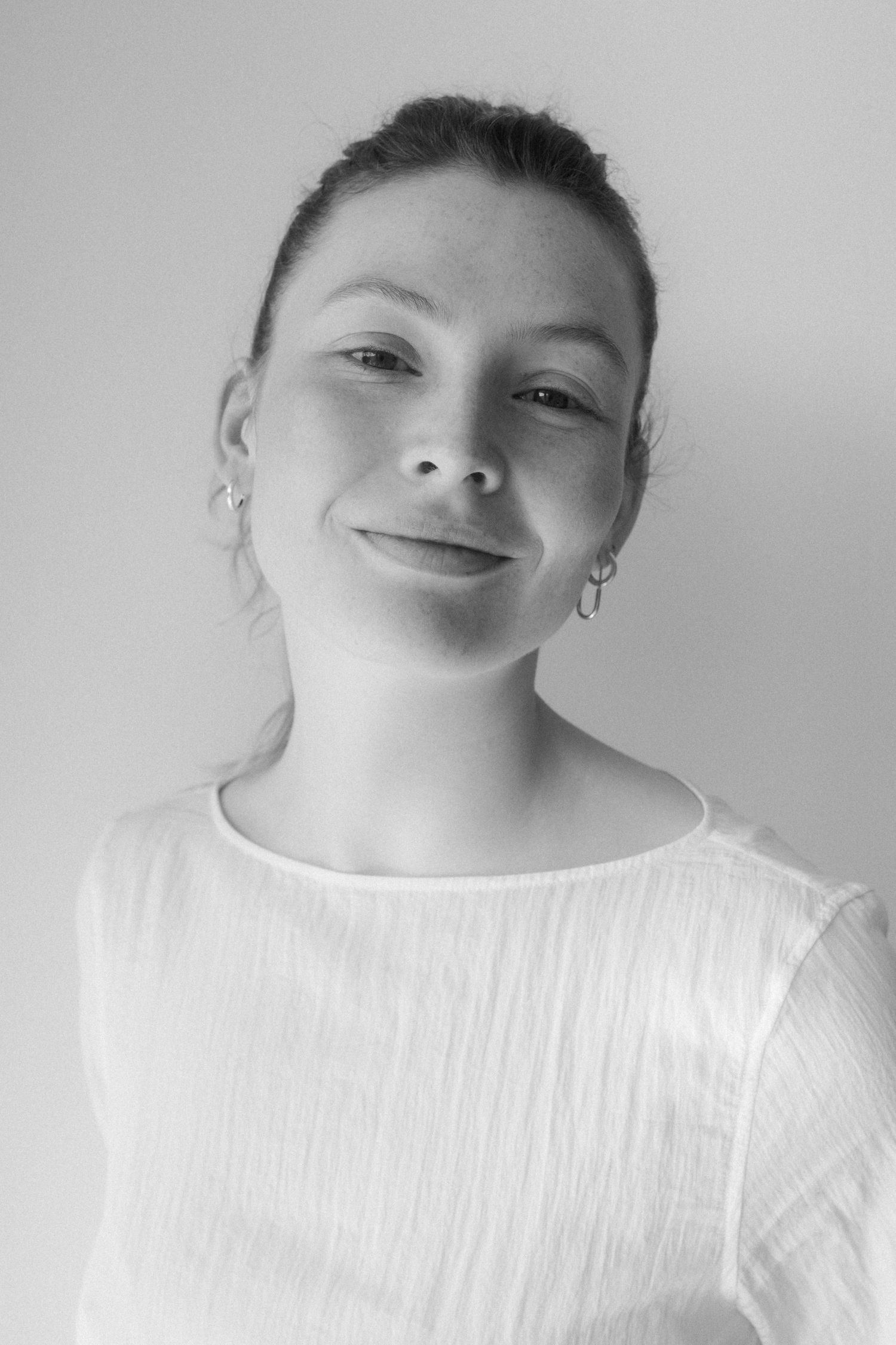 A series of close-up black and white portraits showing someone wearing a white top against a light background.