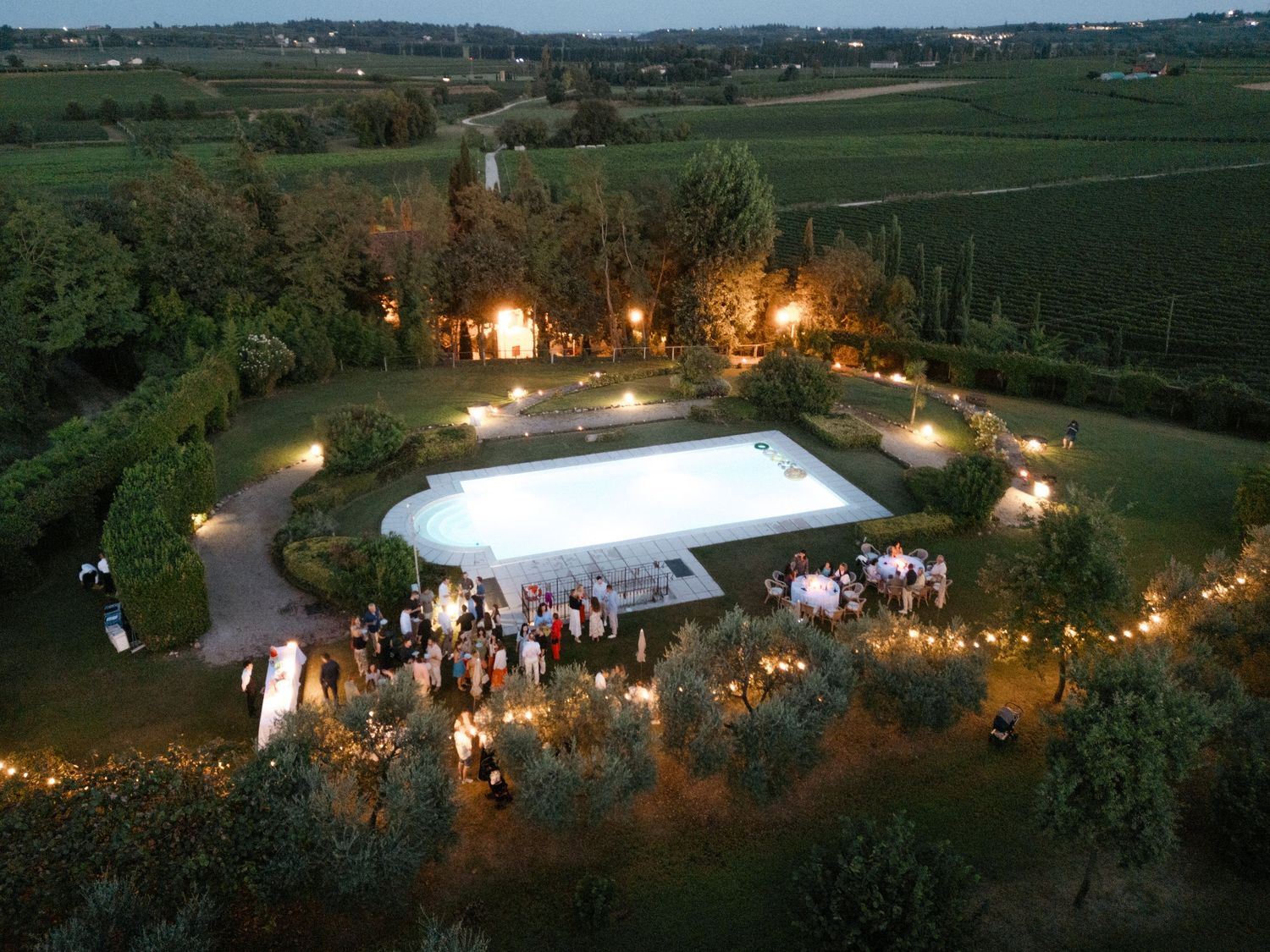 Panoramic aerial view of an outdoor wedding reception venue with tents and lighting at dusk.