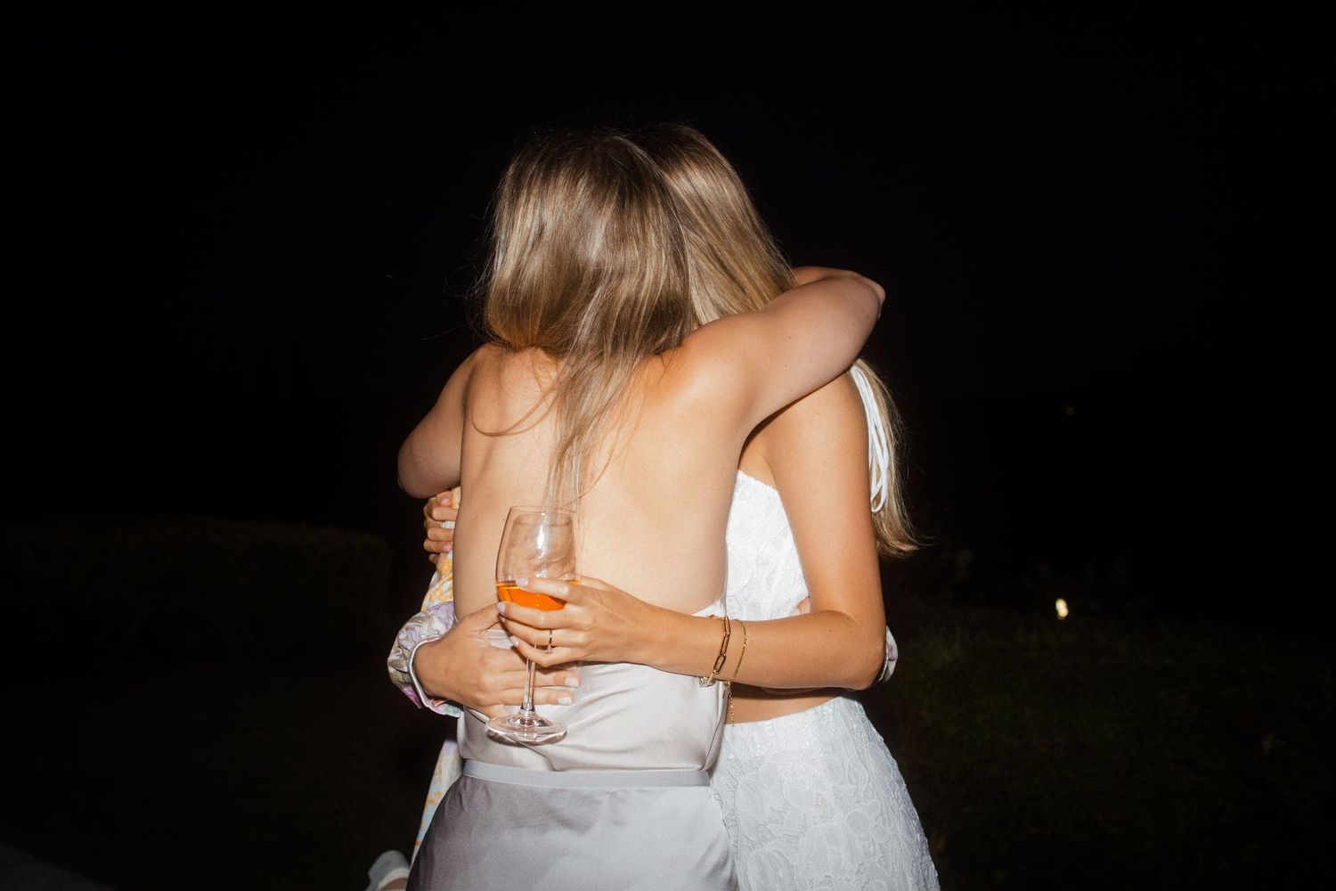 Friends embracing during an evening outdoor celebration.