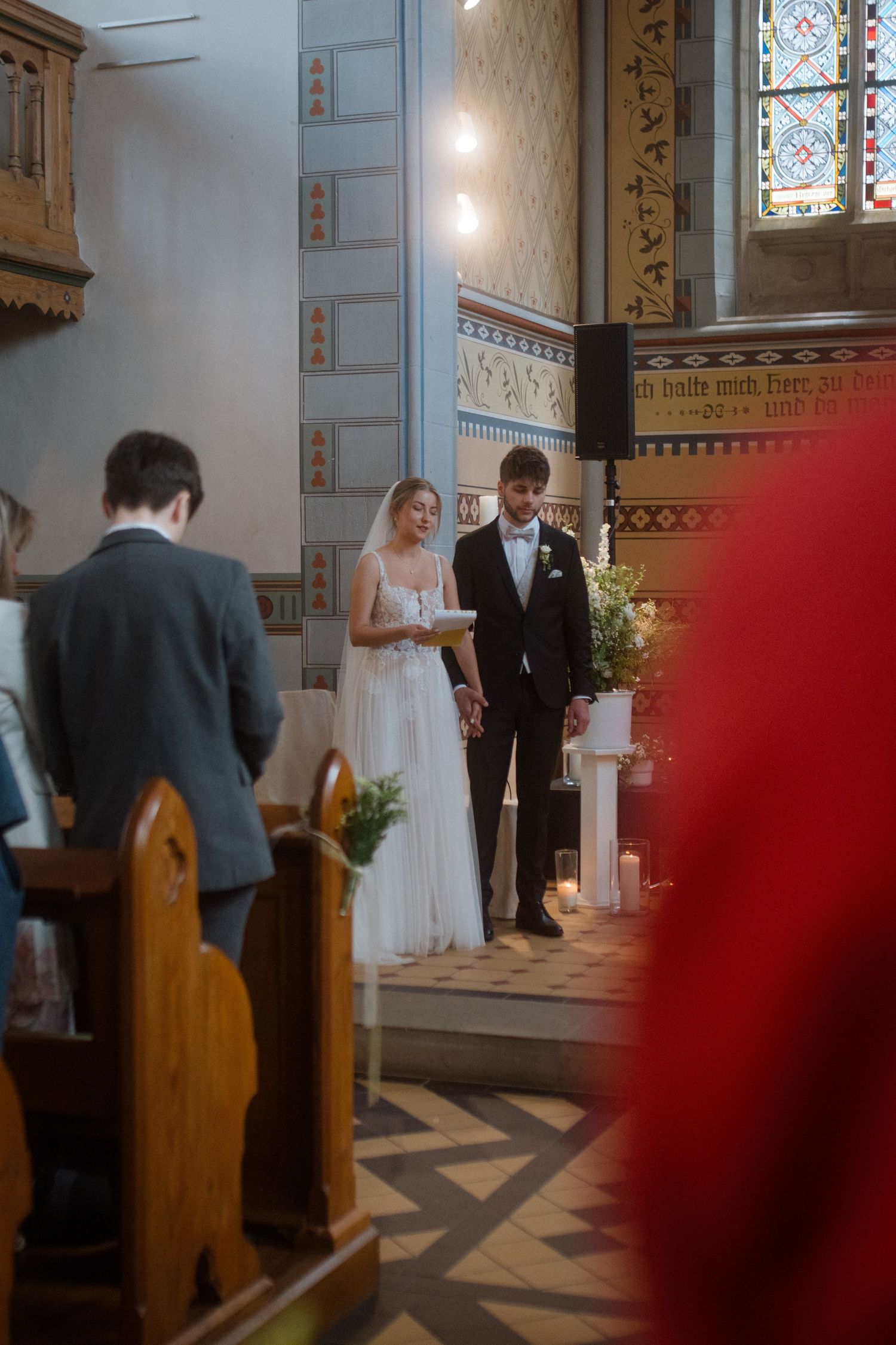 A couple stands at the altar during their wedding ceremony in a church.