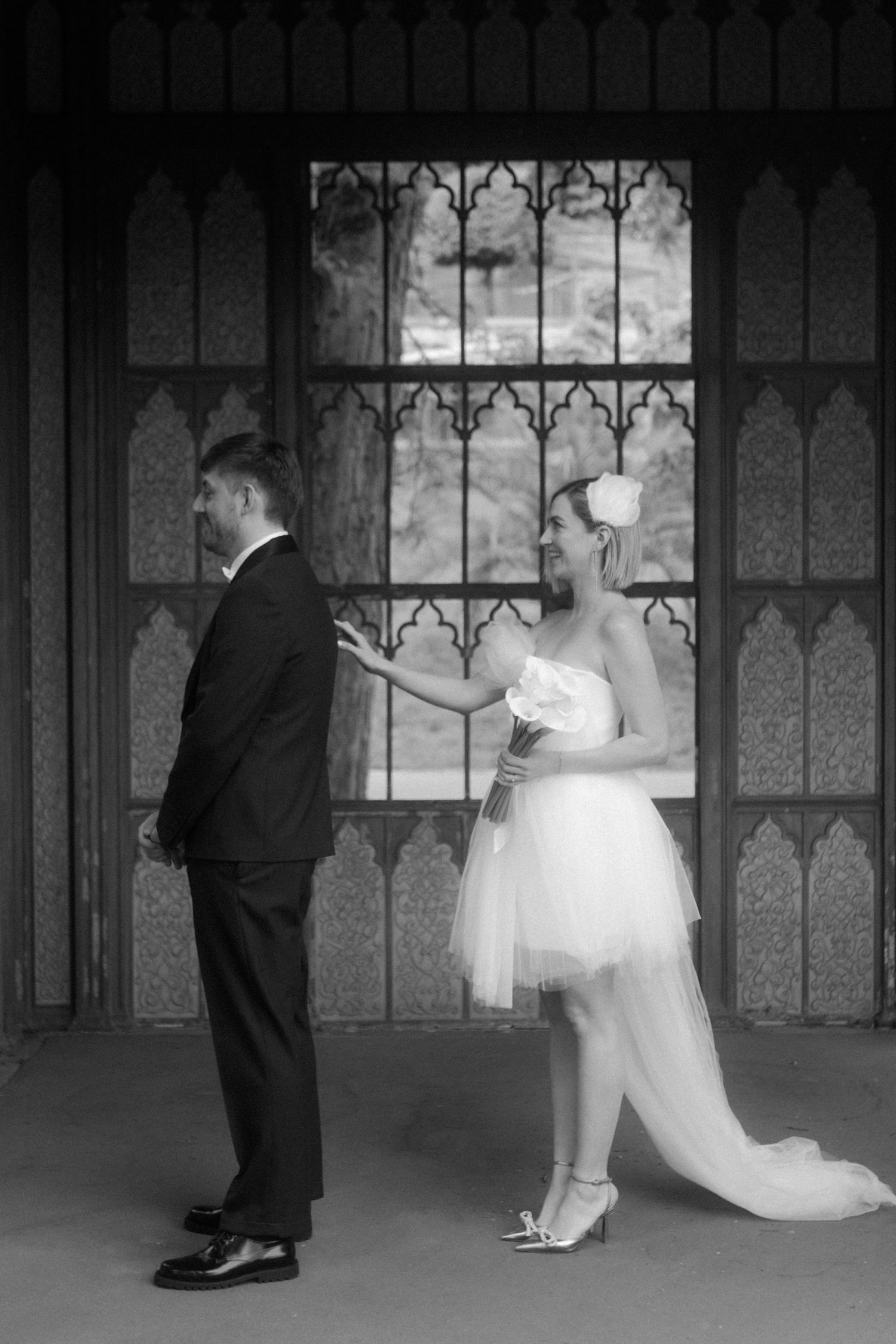 Stylish black and white photo of a couple in wedding attire standing back-to-back.