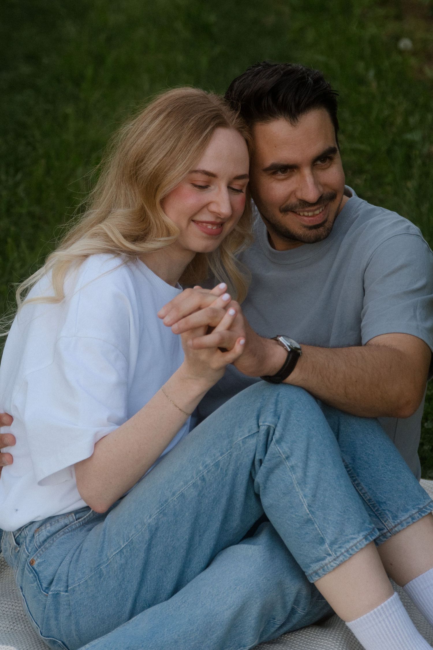 A couple shares an intimate moment while sitting together in casual denim and t-shirts.