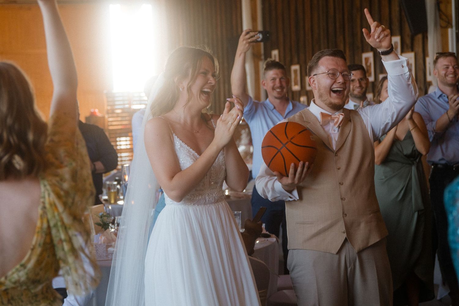 Wedding guests celebrating and clapping during a joyous reception moment.