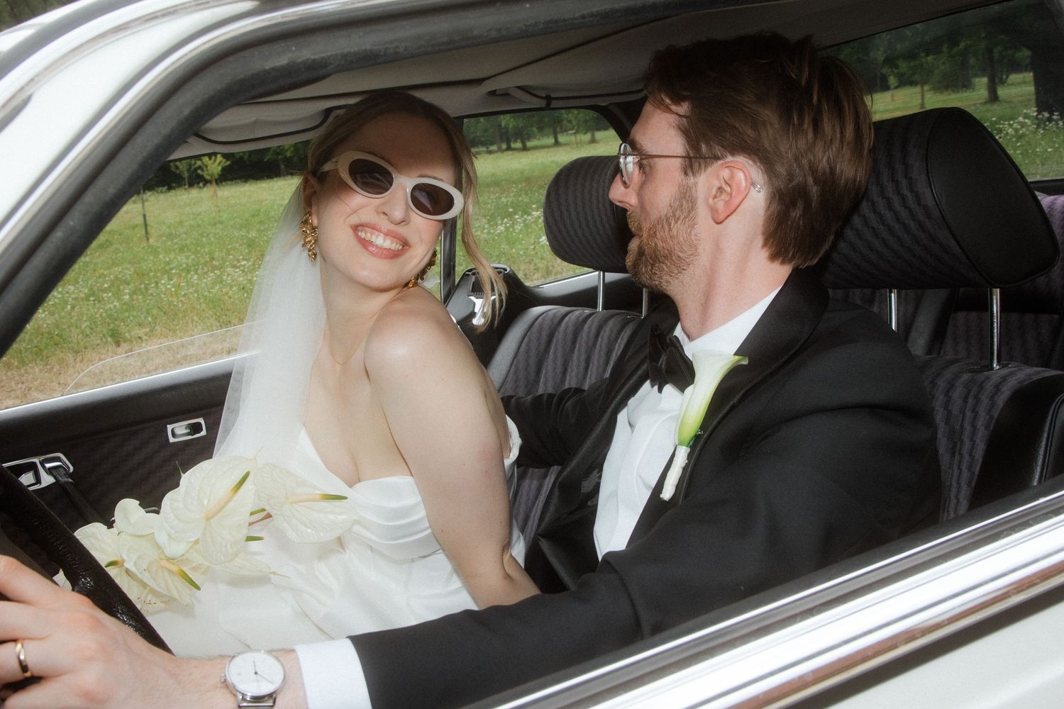 Newlyweds share intimate moments while sitting in their wedding car.