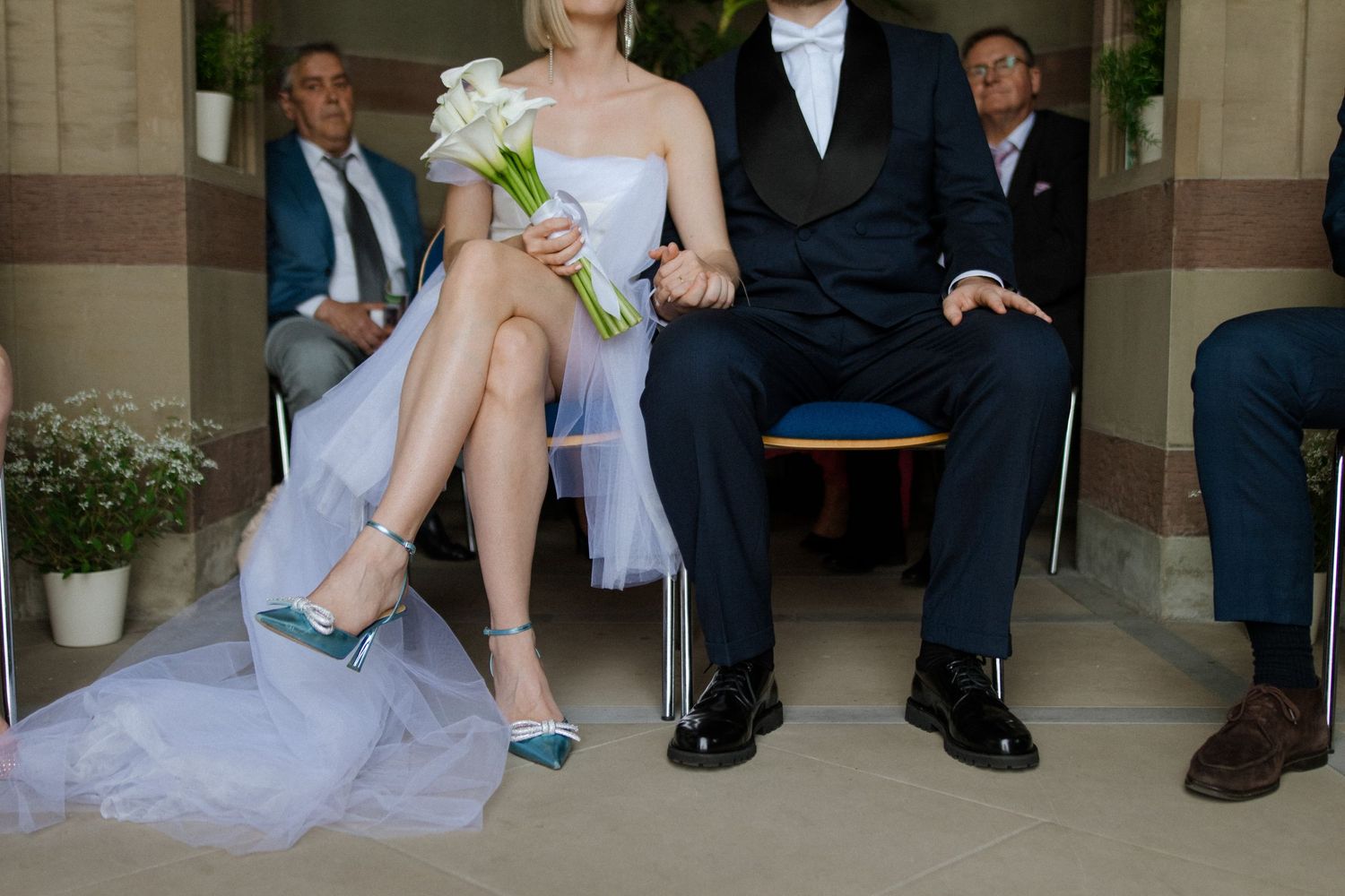 Close-up detail of formal attire and teal shoes at an elegant wedding ceremony.