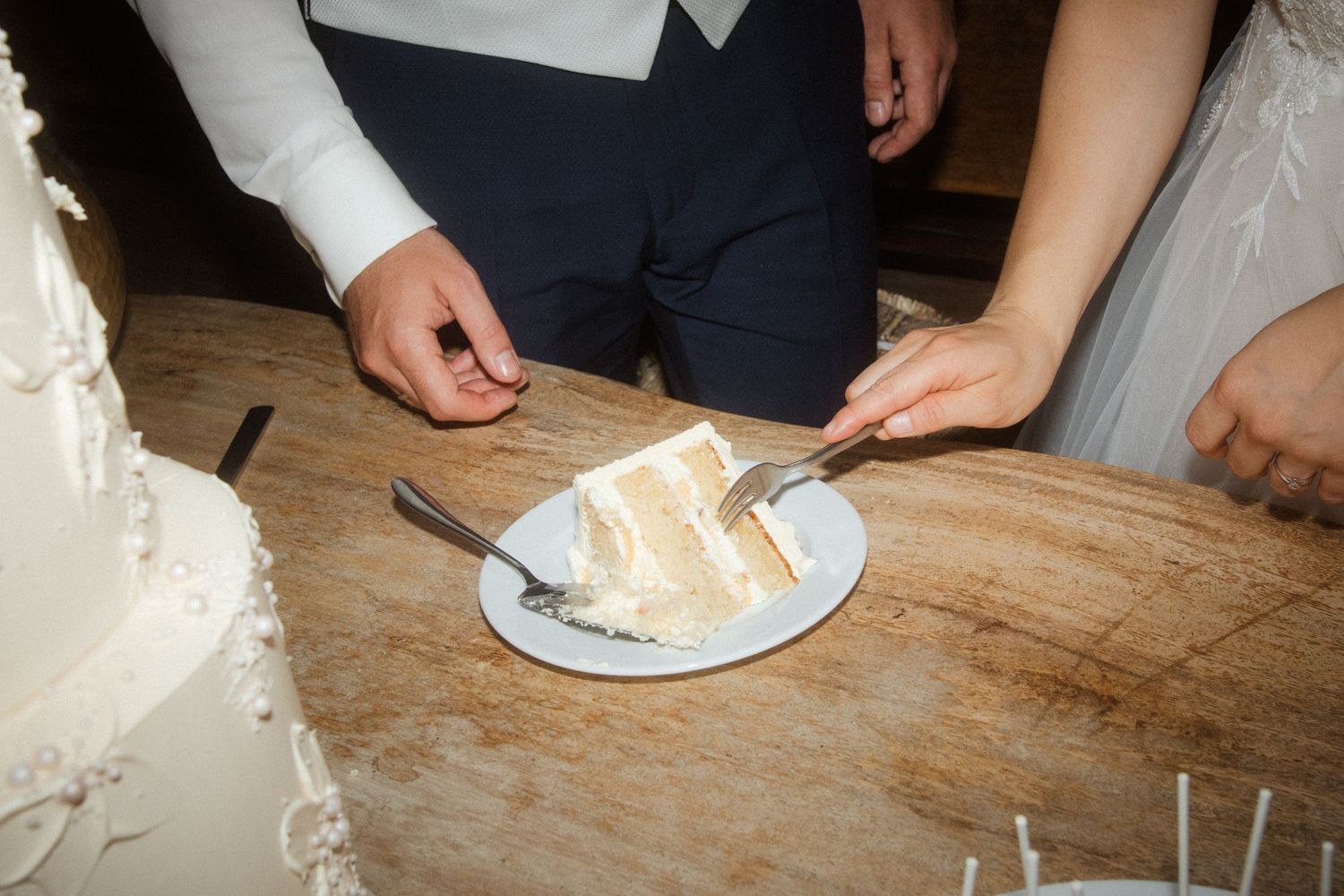 Close-up shot of wedding cake being cut and served on a wooden table.
