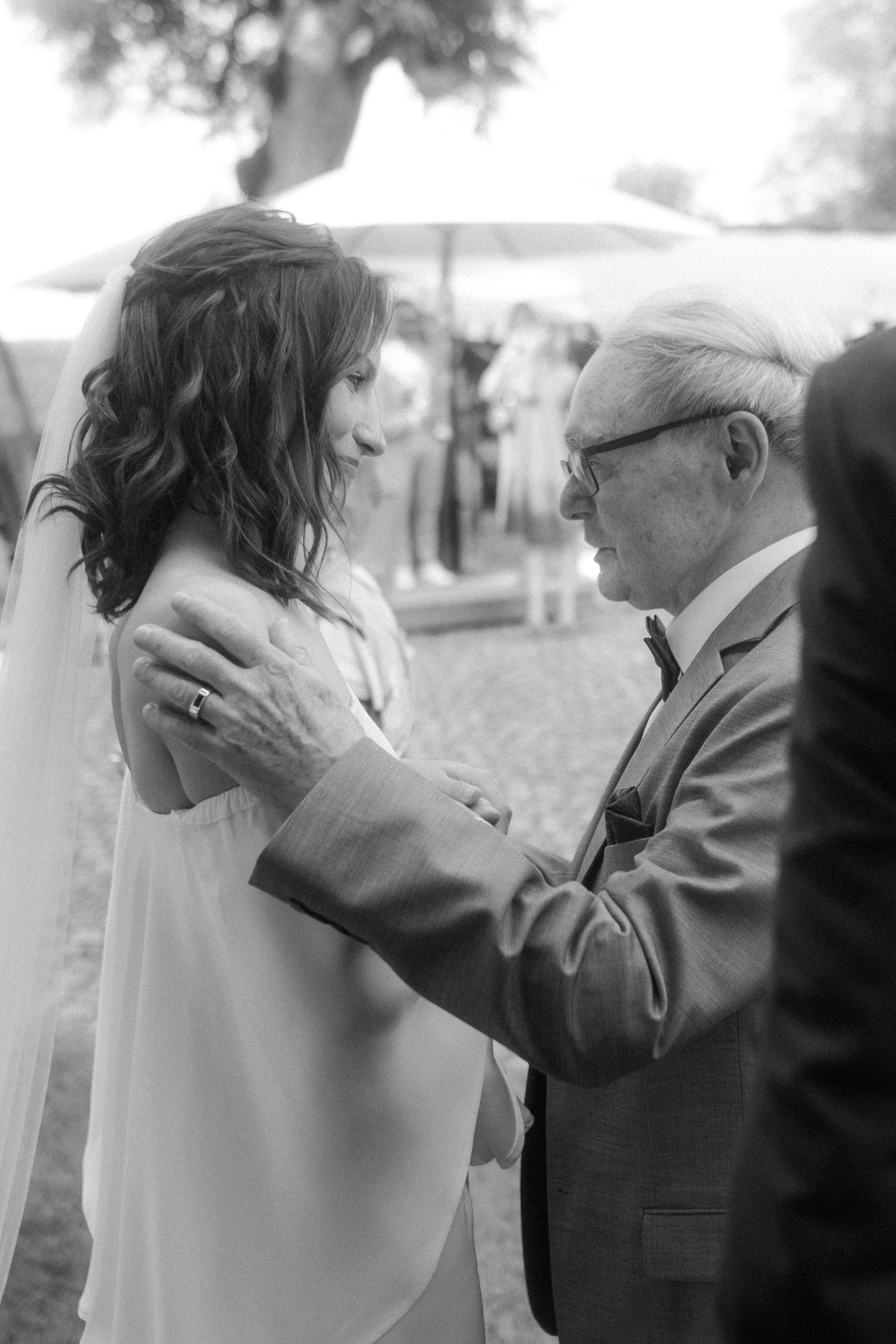 Black and white photo capturing tender moment between guests at wedding reception.