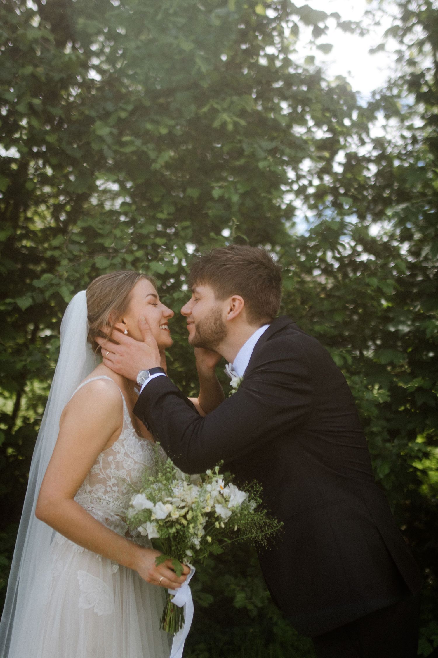 Romantic wedding portrait of couple sharing an intimate moment in a sunlit garden.