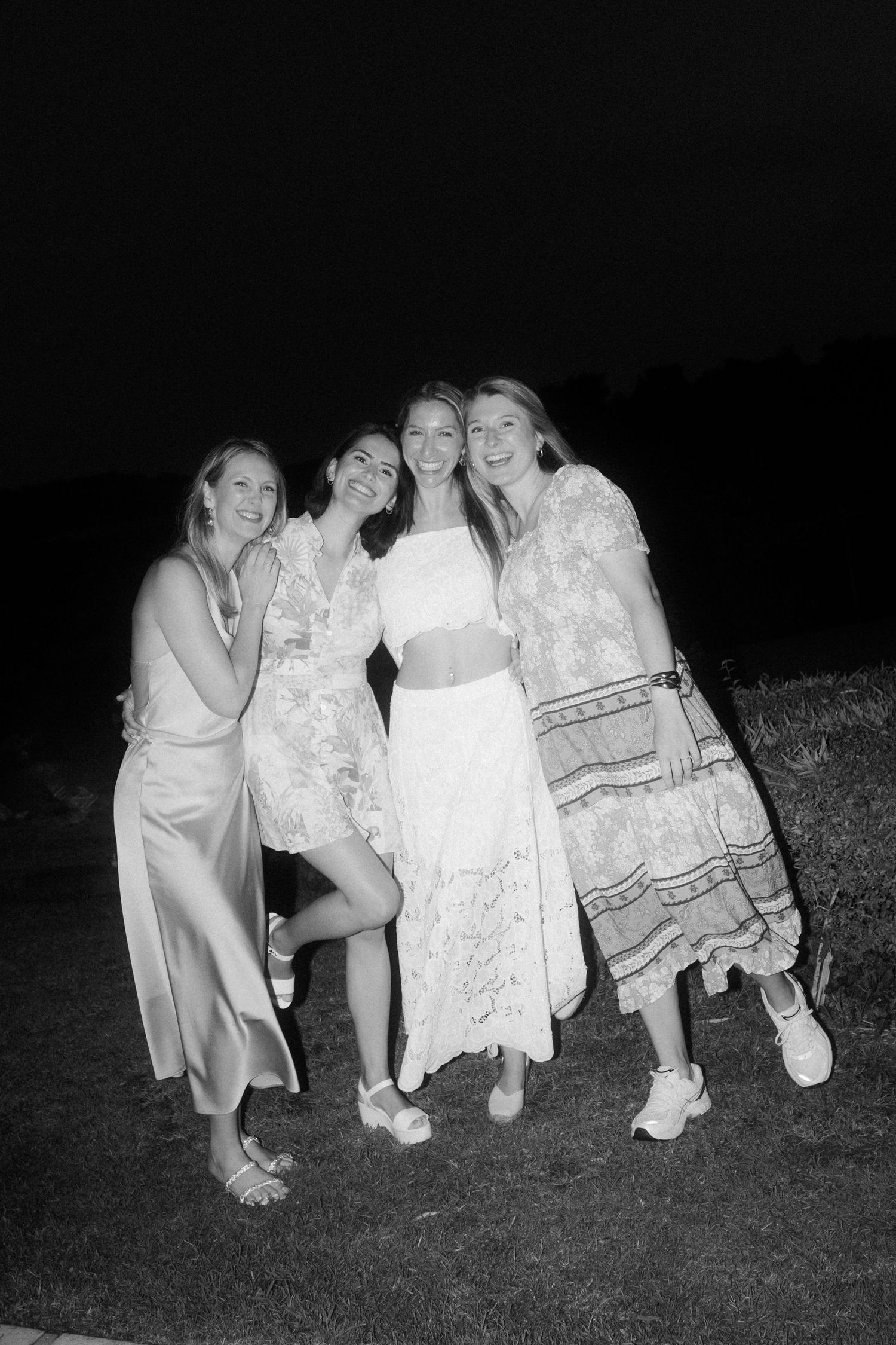 A group poses together on the grass during a nighttime celebration.