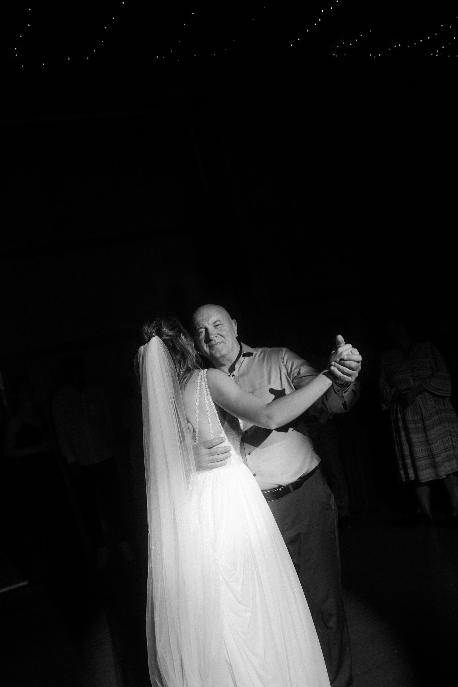 Couple dancing in dim lighting with flowing white wedding dress.