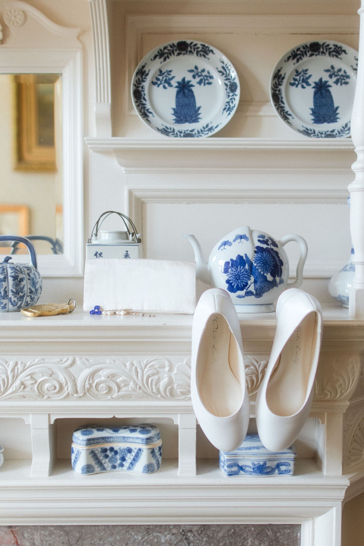 Blue and white china plates and teapot displayed on ornate white shelves with white ballet flats.