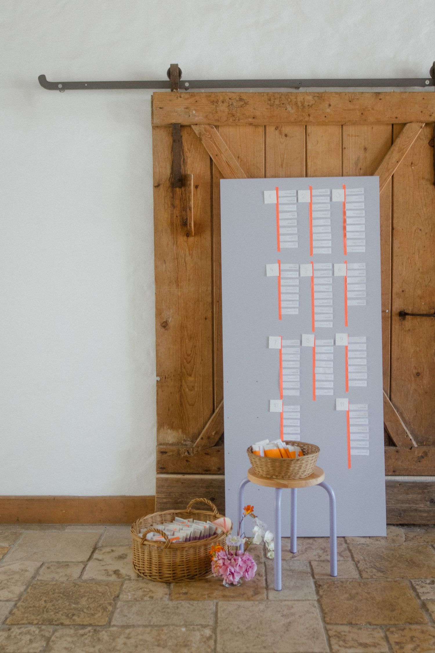 Wedding seating chart board against rustic wooden door with floral decorations.