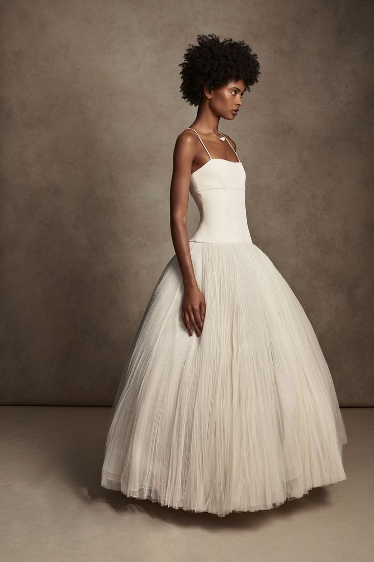 A structured white ballgown wedding dress with a fitted bodice and full tulle skirt photographed against a brown backdrop.