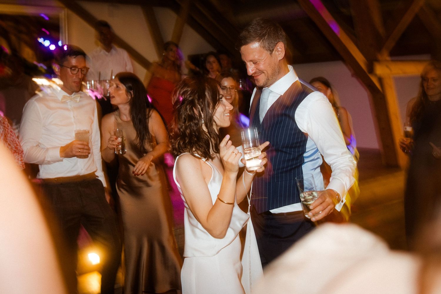Couple dancing together at a wedding reception under ambient lighting.