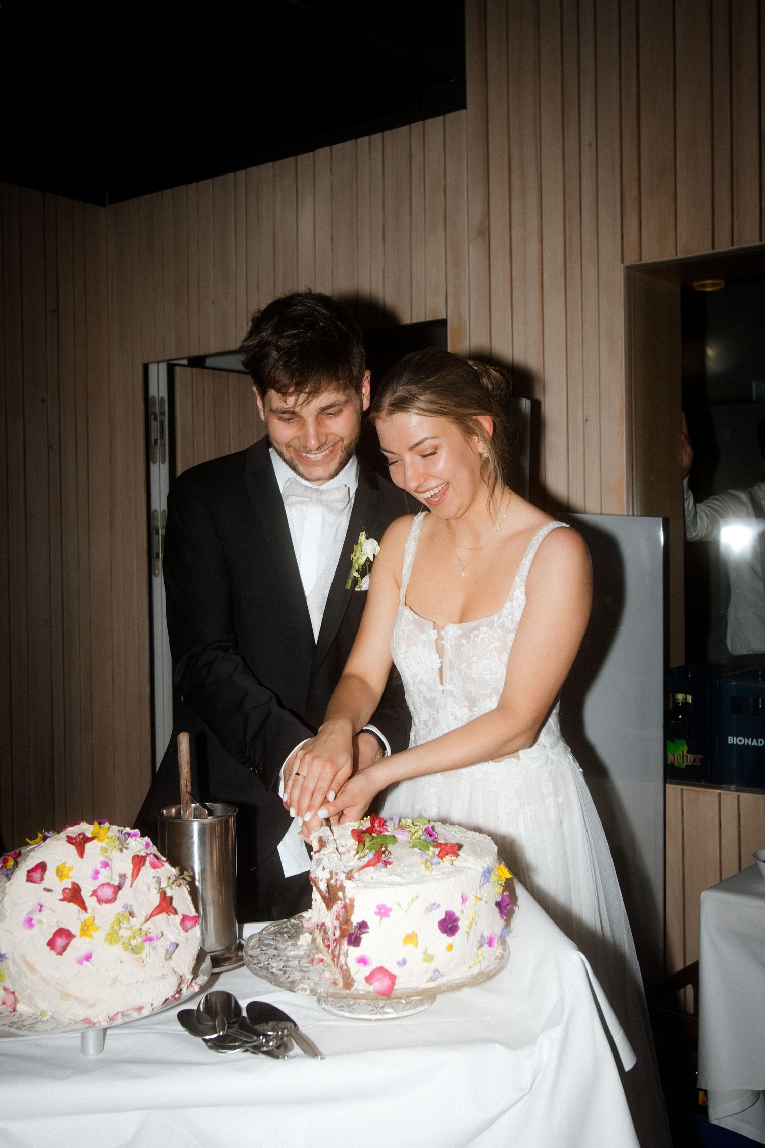 A couple cuts into their floral decorated wedding cake together.