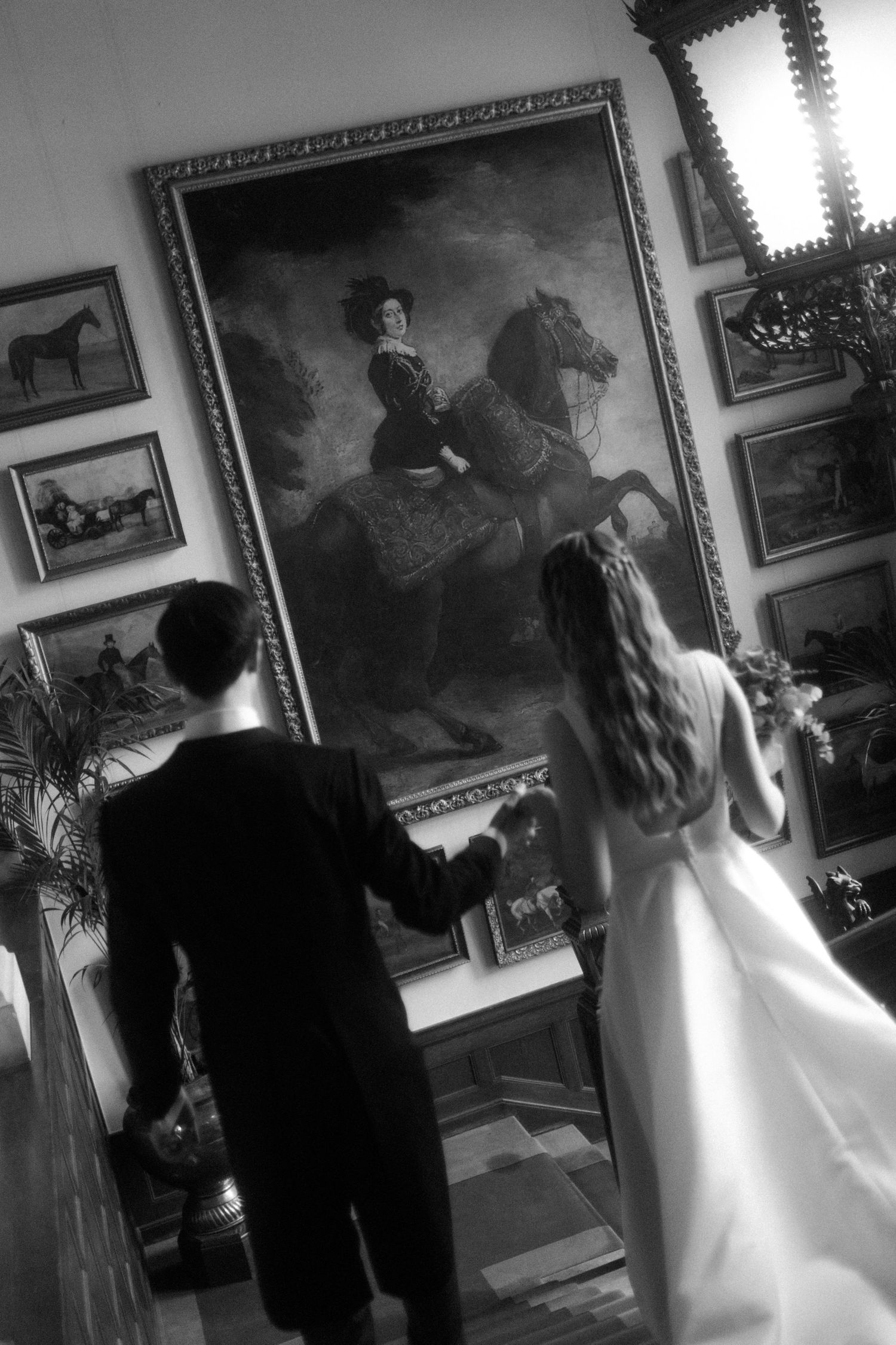 A couple admires a large equestrian painting in an ornate gallery setting.