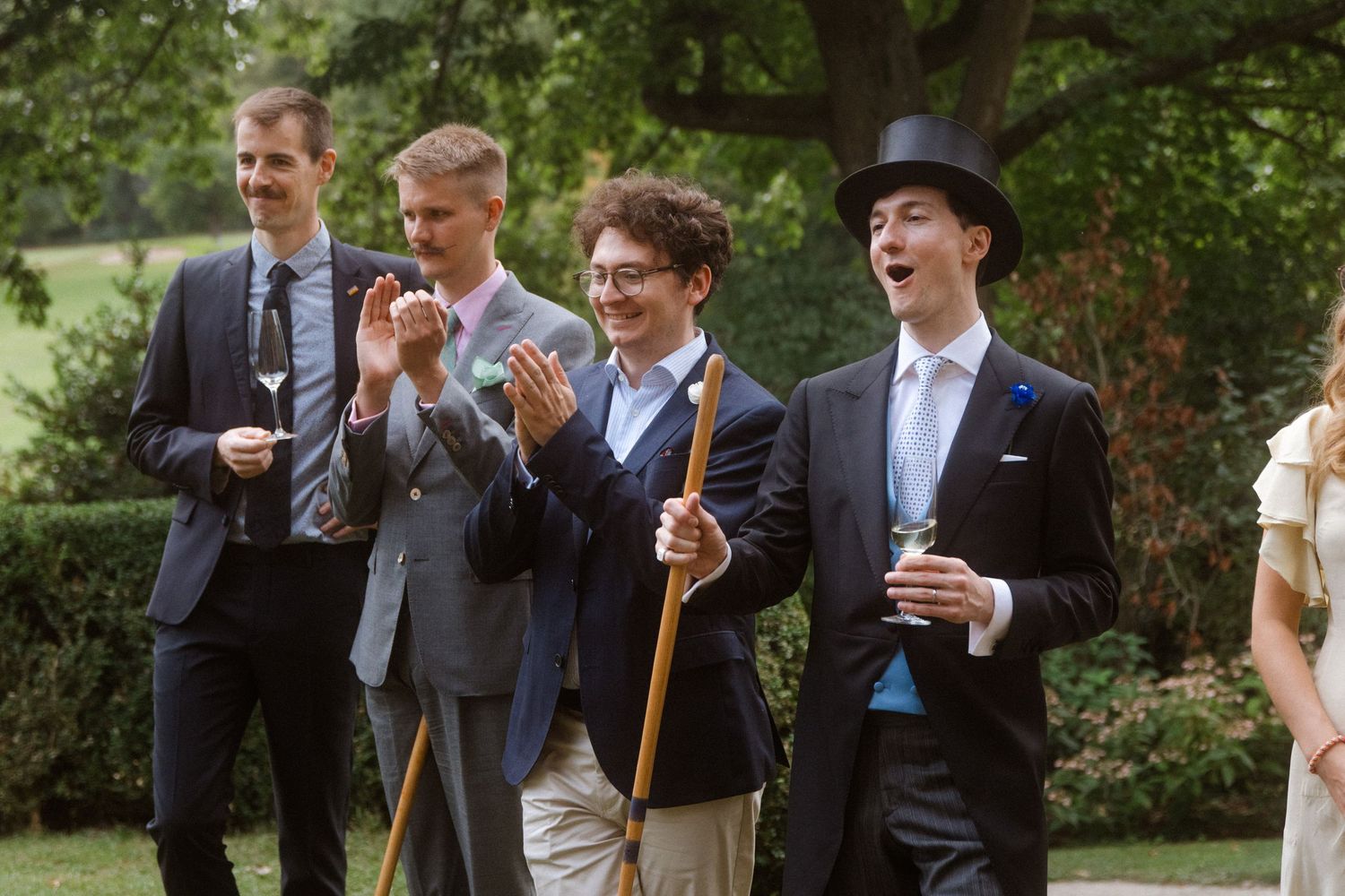 Wedding guests laughing and enjoying a game of croquet in a garden setting.