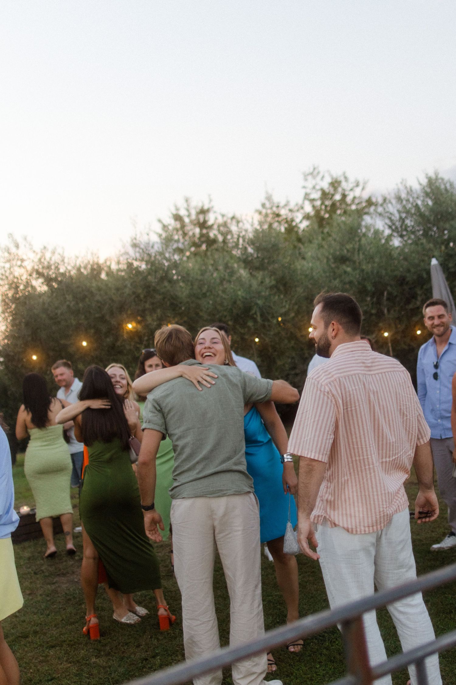 Guests mingle at an outdoor garden party during sunset.