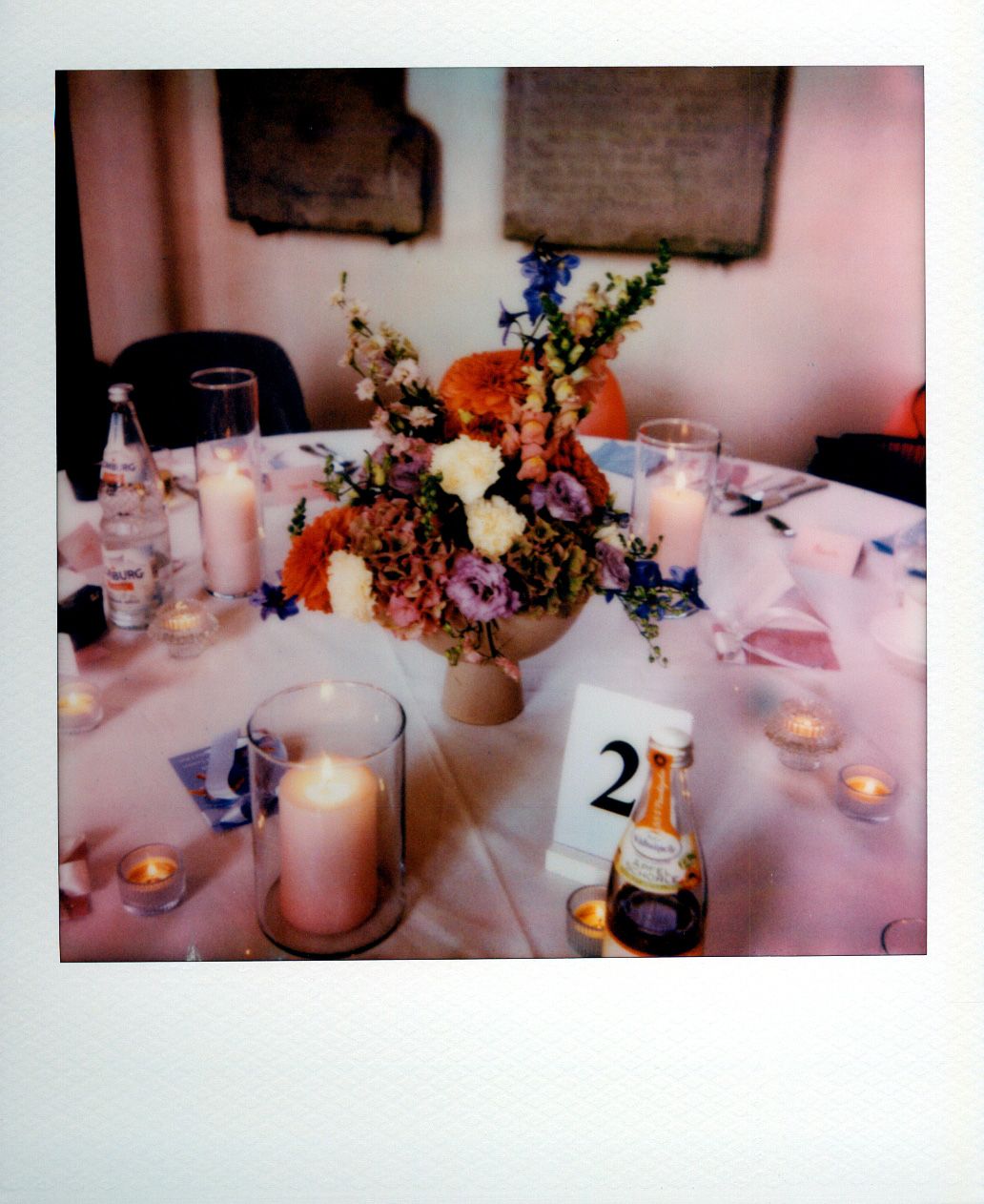 Table settings with white linens, glowing candles, and floral centerpieces featuring purple and blue blooms at a formal event.