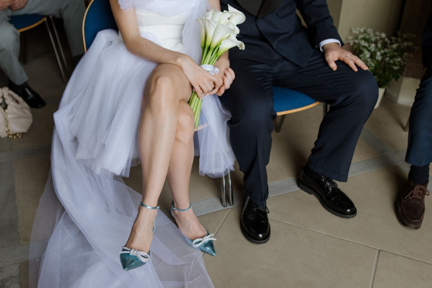 Detail shot of blue shoes and white dress fabric against formal attire.