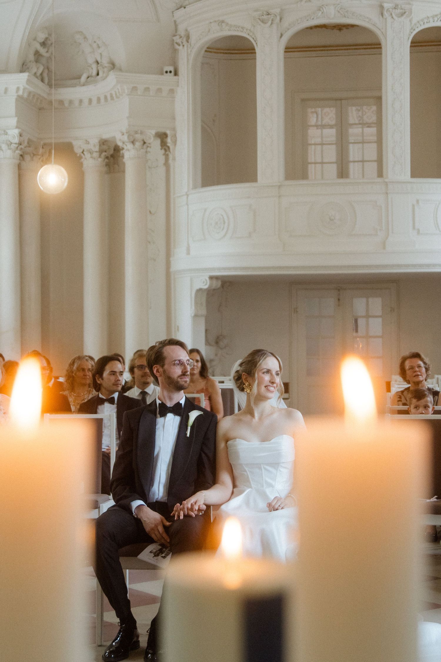 Romantic candlelit wedding ceremony in a grand white columned hall.