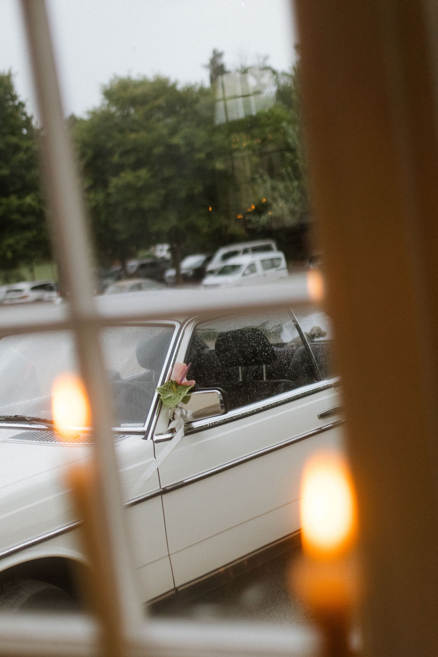 View through window of white vintage limousine with candles in foreground.