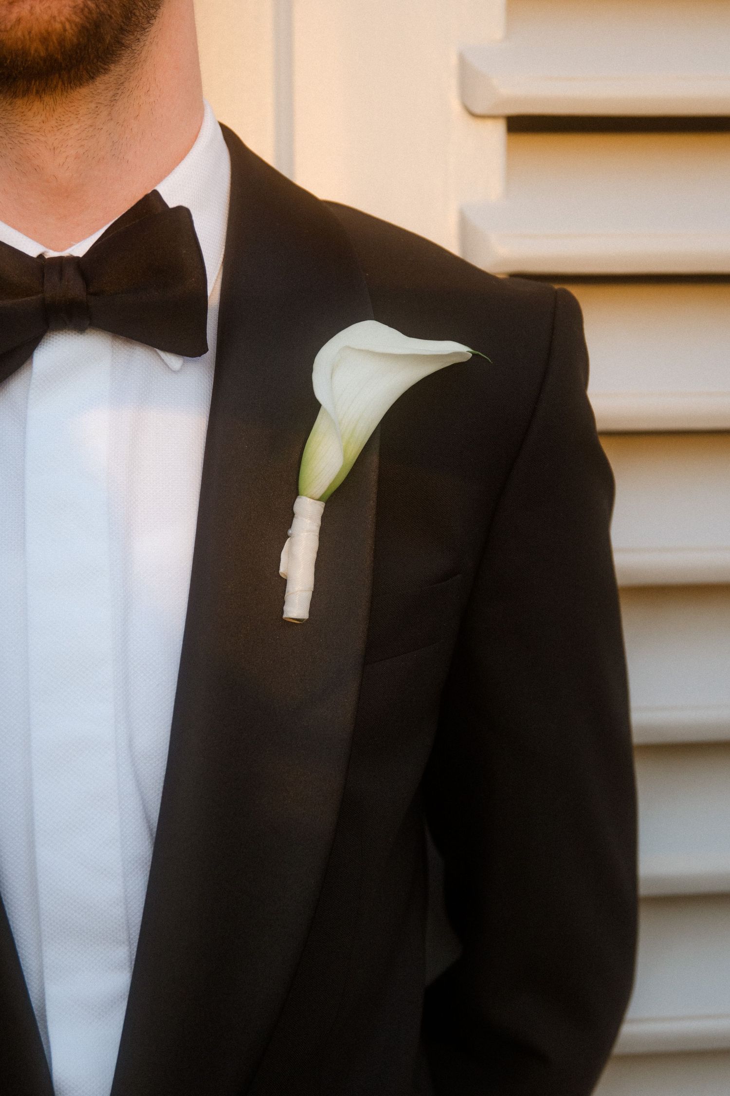 Multiple detail shots of a white calla lily boutonniere on a black tuxedo jacket.