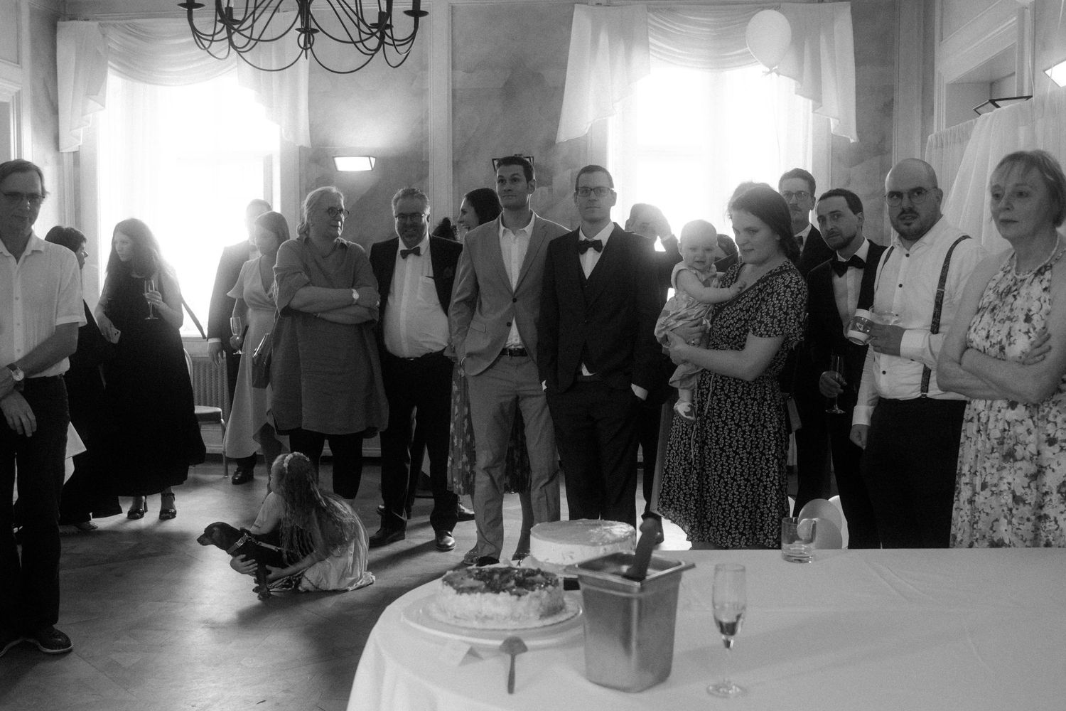 Black and white photo of wedding reception guests mingling in an elegant indoor venue.