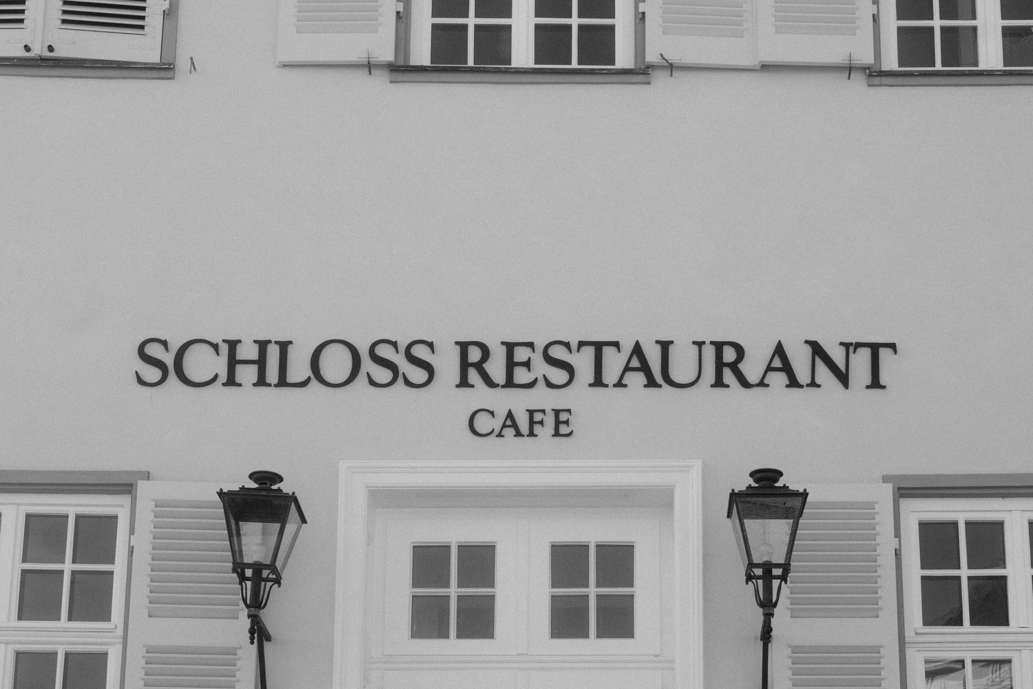 Exterior signage for Schloss Restaurant and cafe on classical building facade.