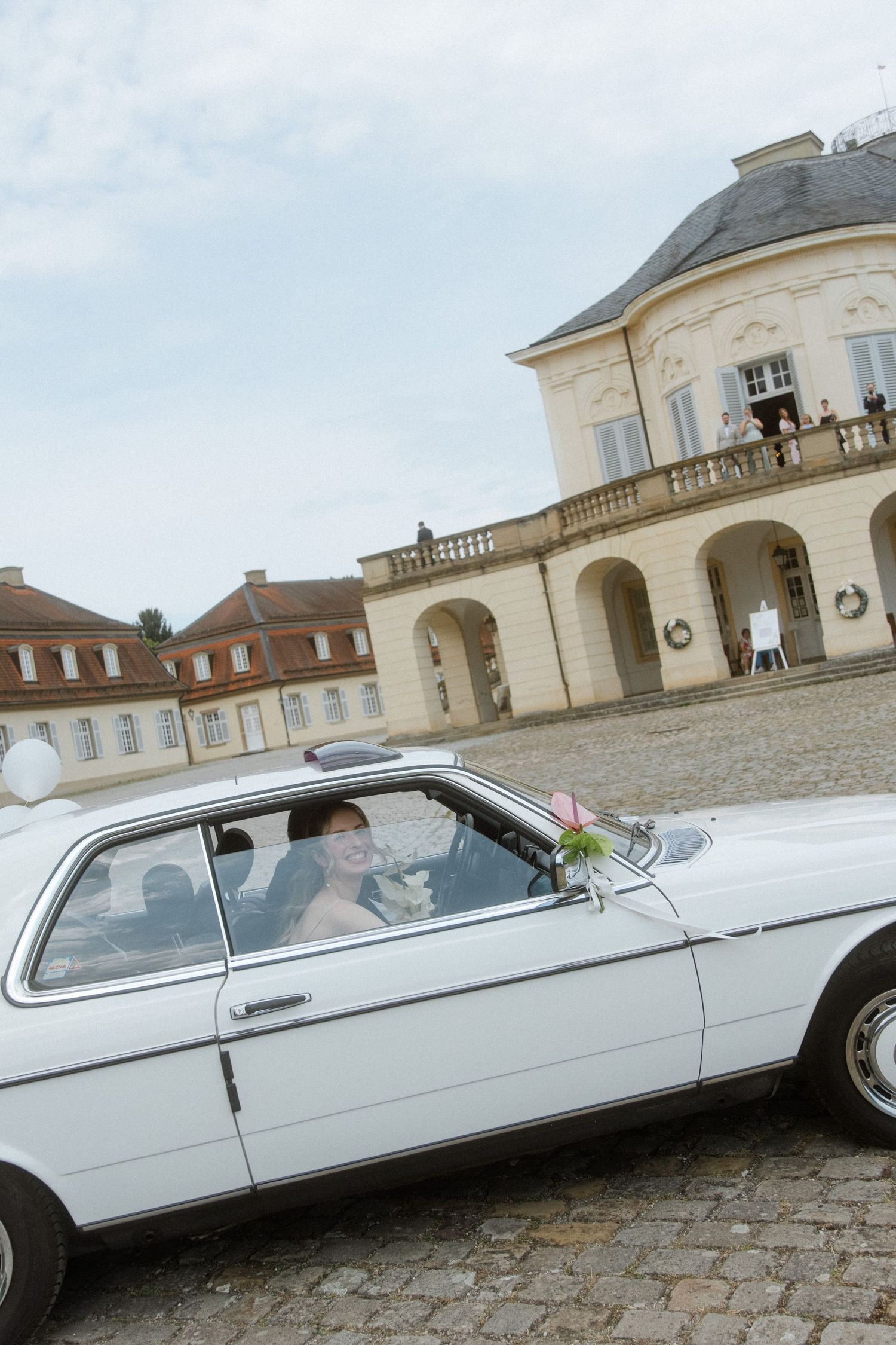 Classic white vintage limousine parked in front of an elegant mansion.