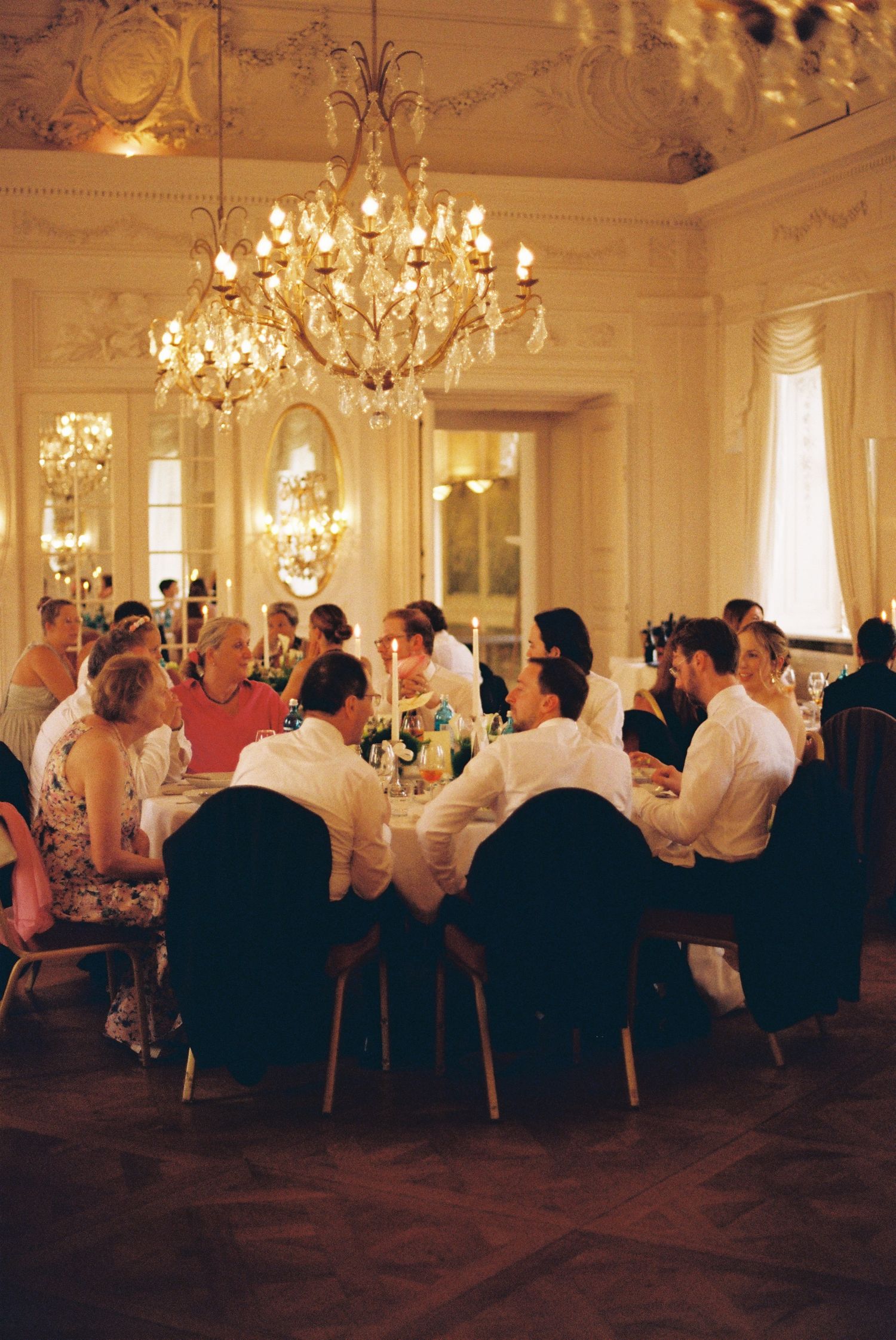 Elegant wedding reception in a grand ballroom with crystal chandeliers and ornate white decor.