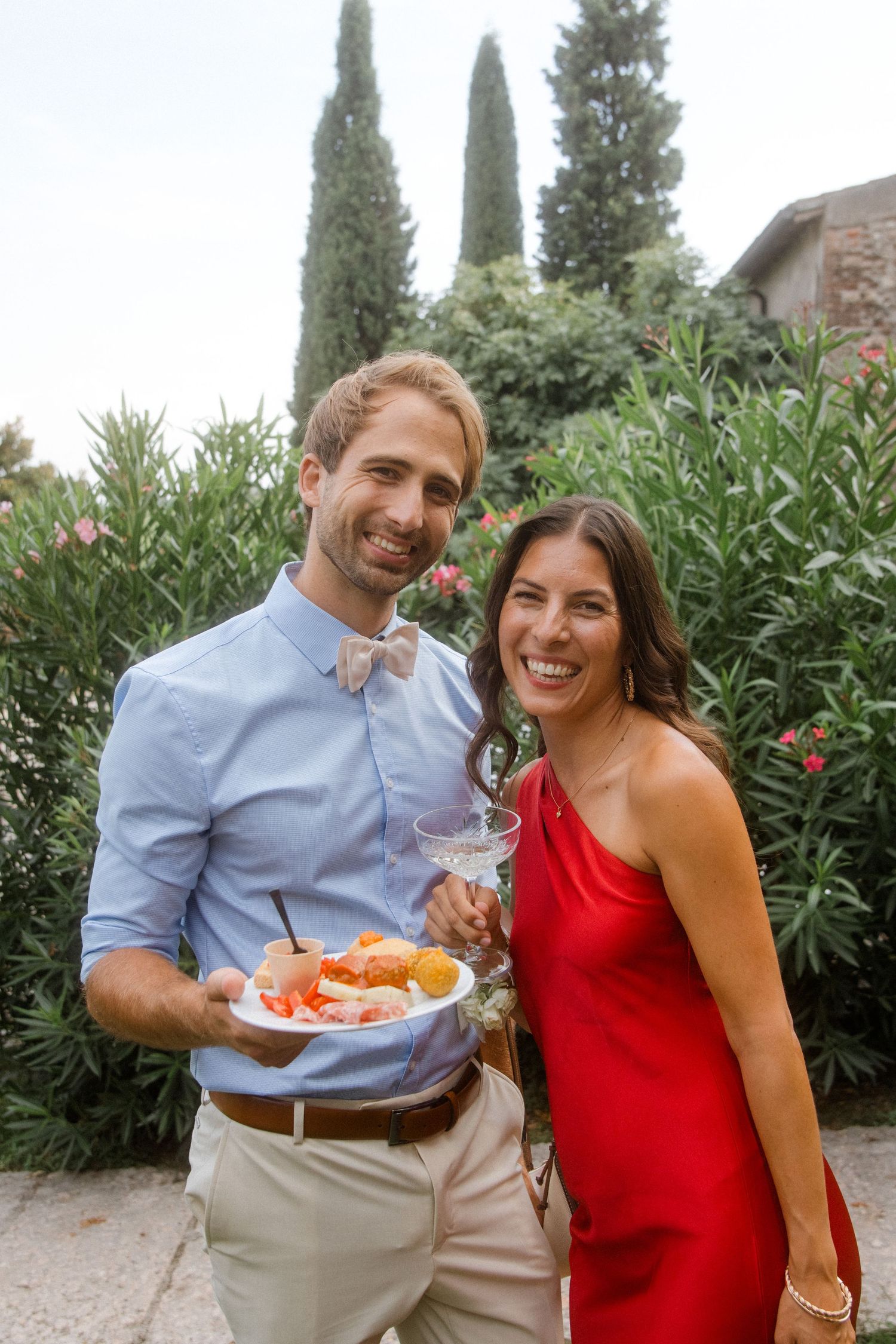 Couple in blue shirt and red dress sharing appetizers at an outdoor party.