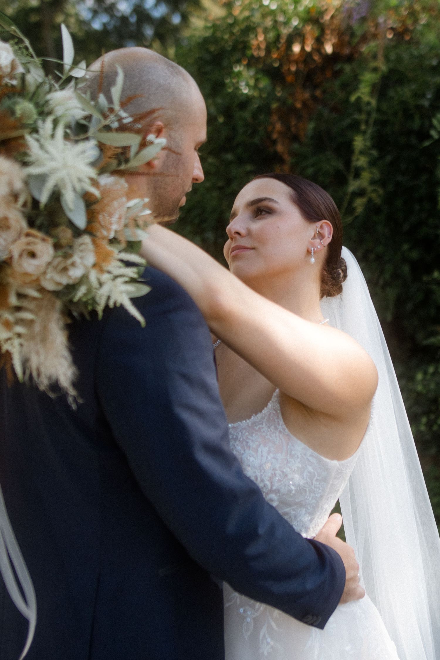 A bride and groom sharing an intimate moment near floral wedding decorations.