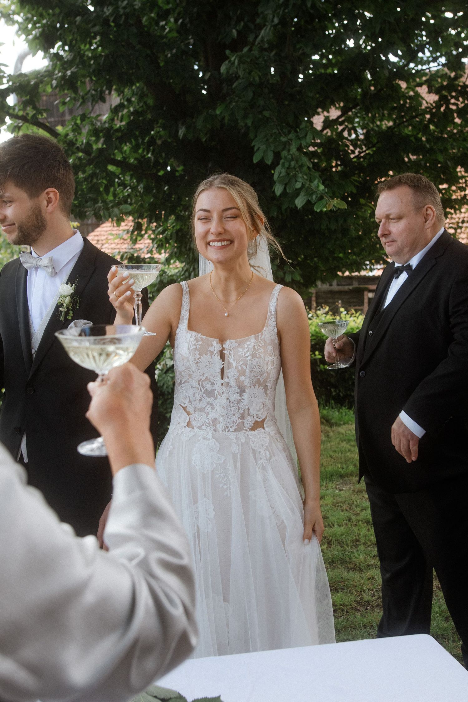 Elegant outdoor wedding reception with champagne toast and formal attire.