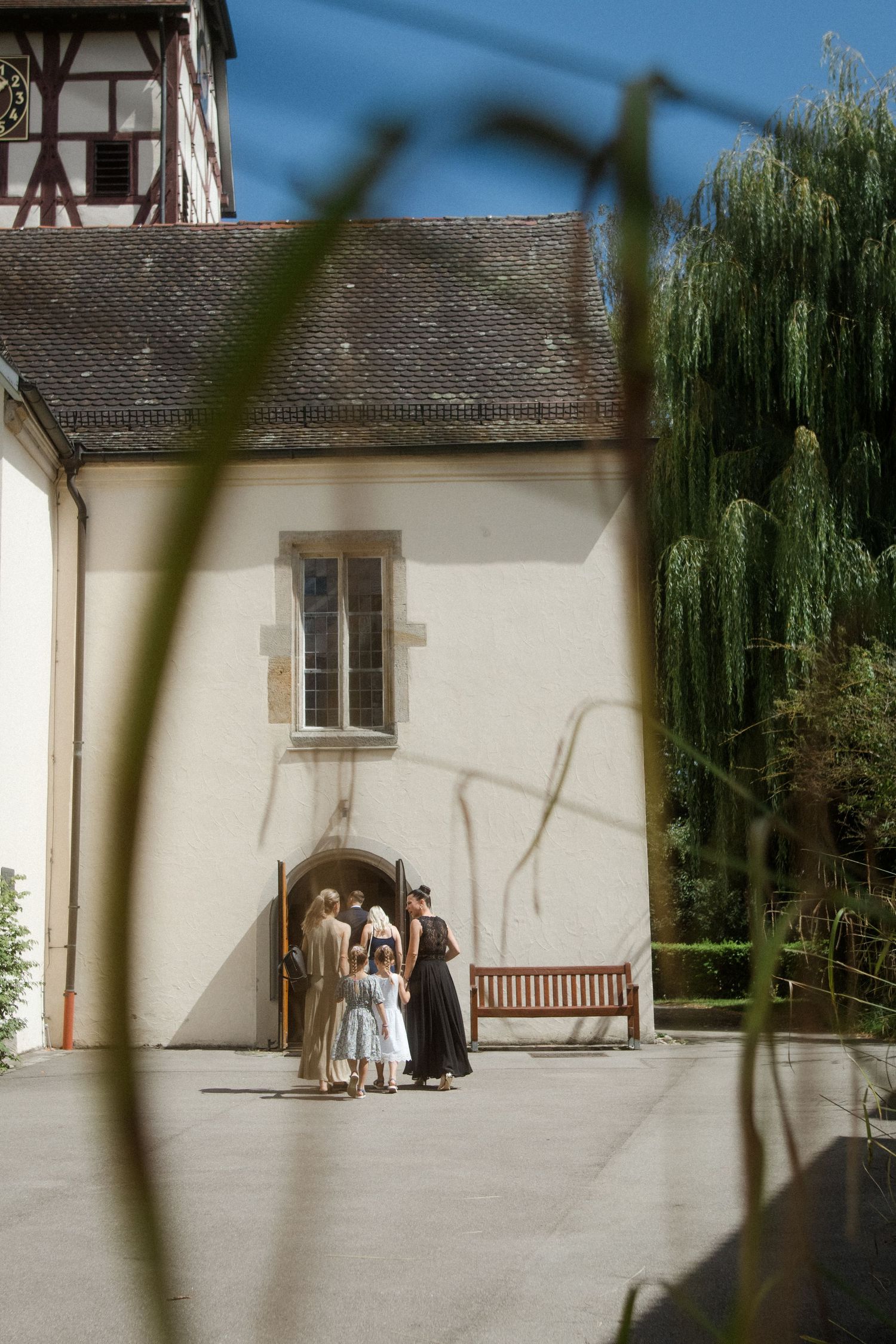 Traditional German building with half-timbered tower and willow tree in summer.