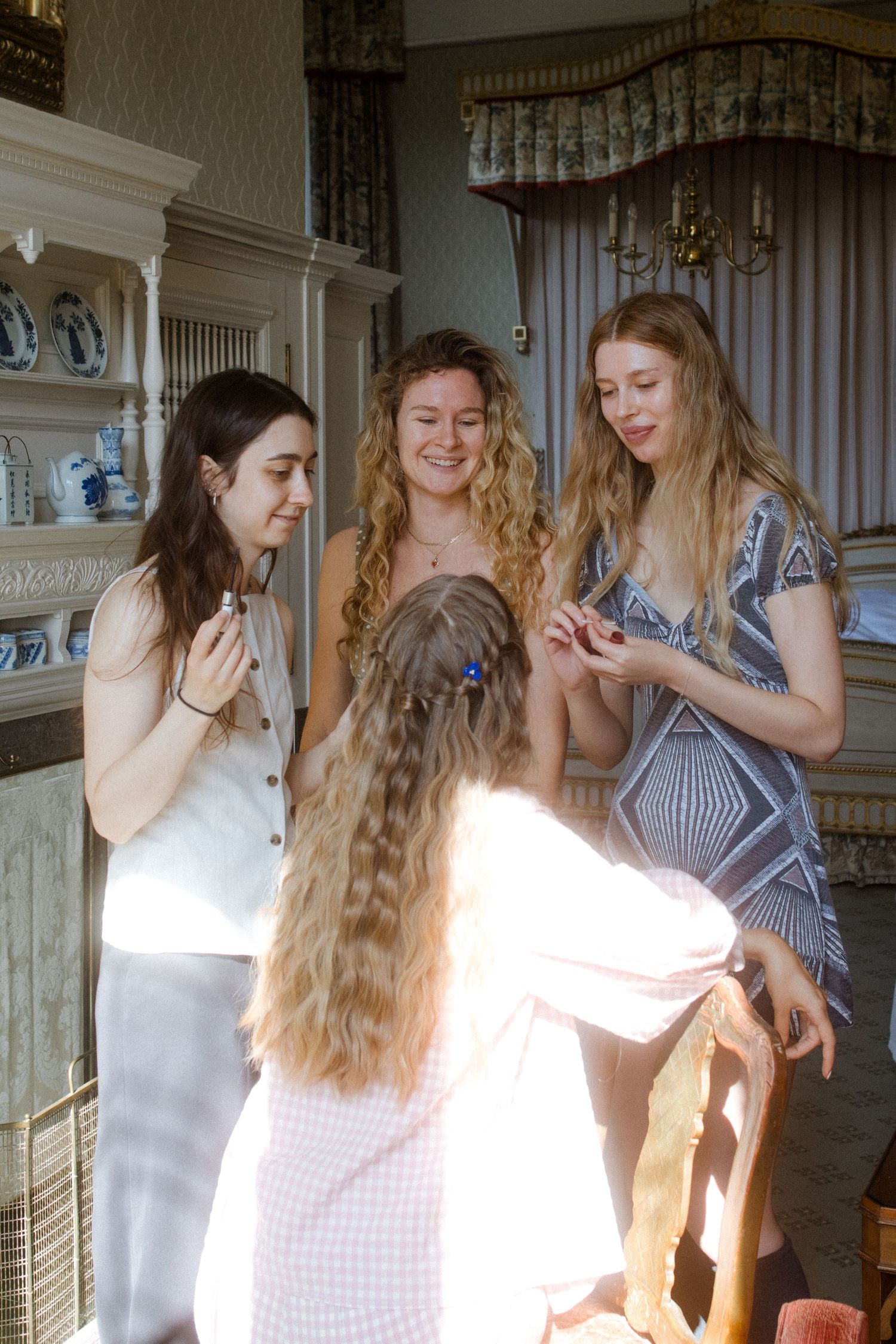 Friends in casual summer dresses share joyful moments in a sunlit vintage room.