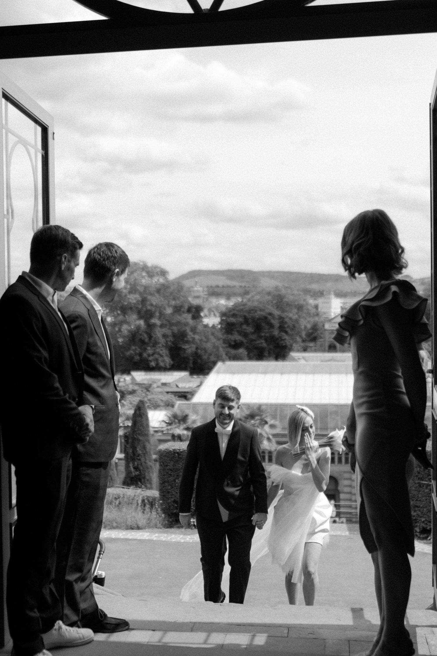 Black and white photograph of a wedding ceremony entrance with scenic backdrop.