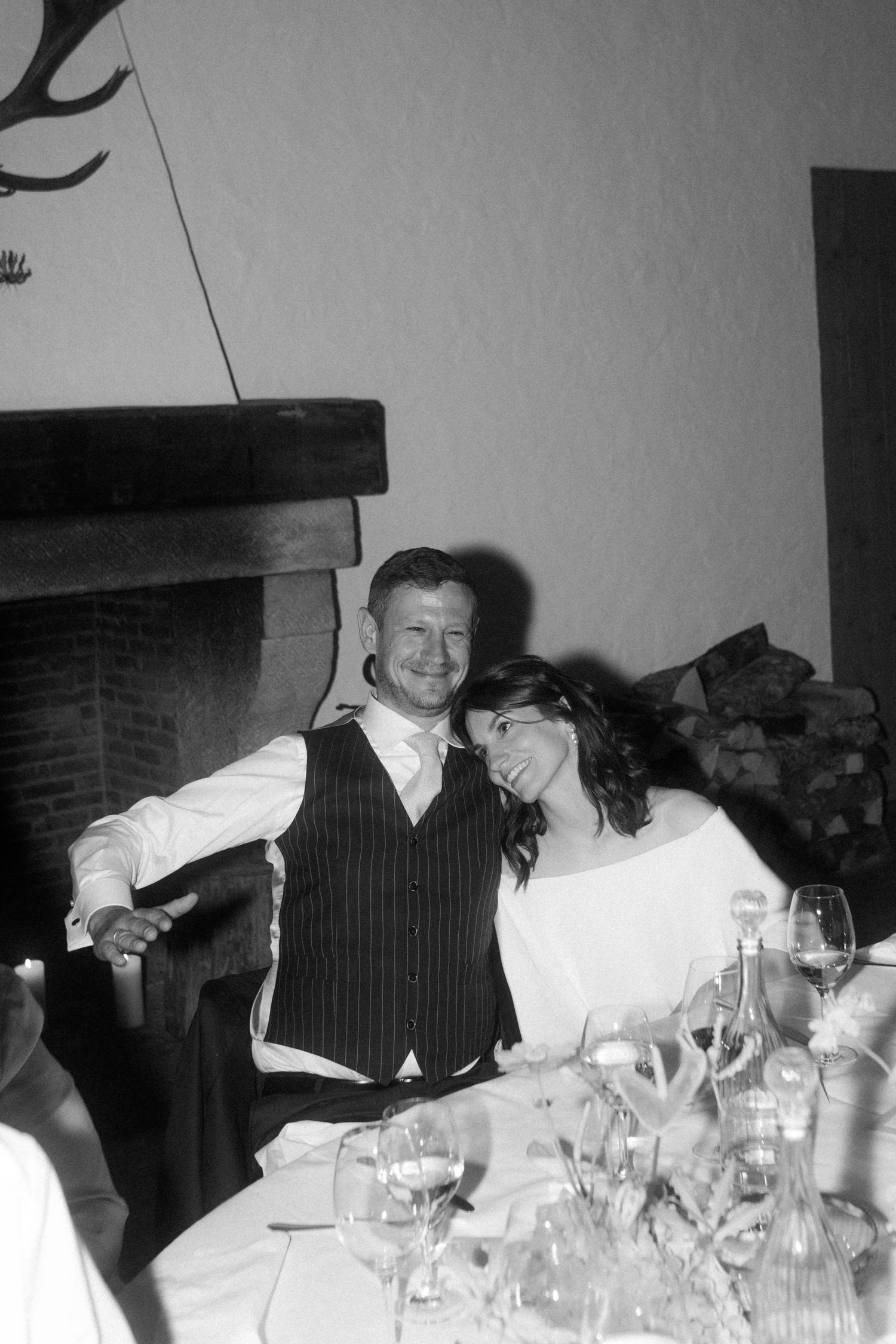 Black and white wedding reception photo with fireplace and antler decor.