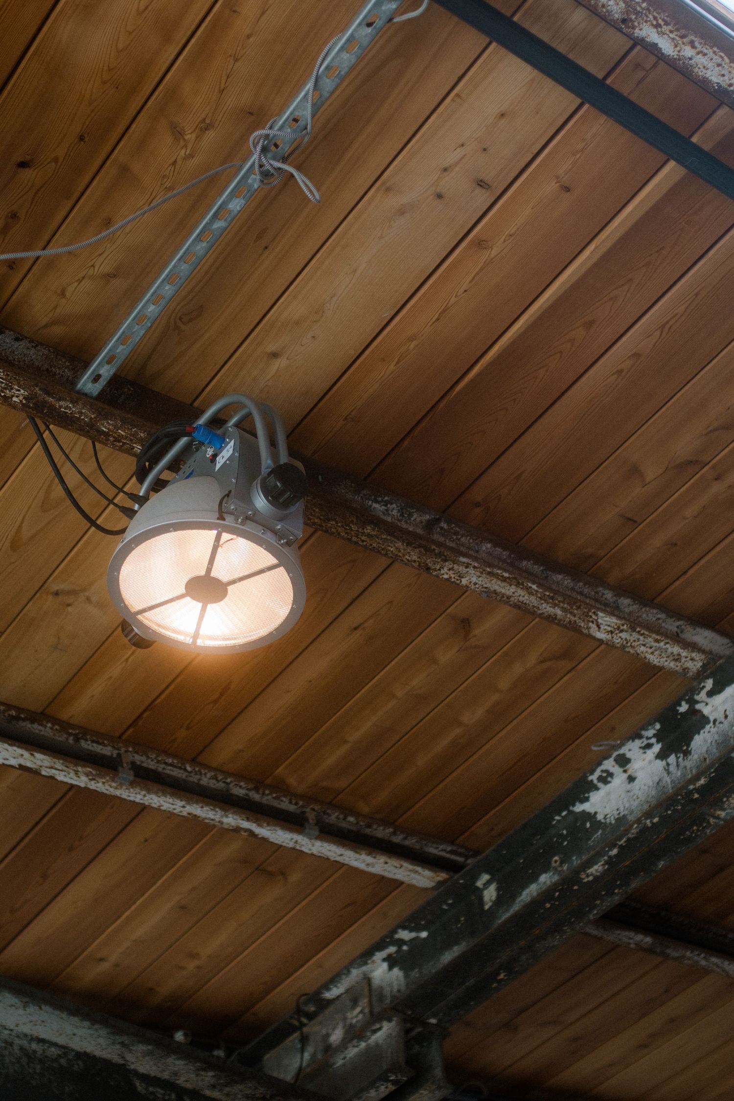 Industrial light fixture mounted on wooden ceiling beams.
