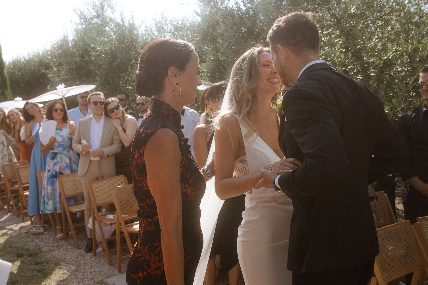 Intimate outdoor wedding ceremony taking place under cypress trees in Tuscany.