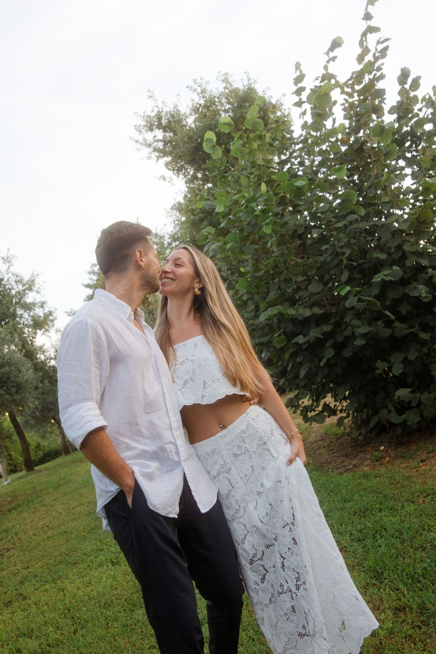 A couple shares an intimate moment in a lush garden setting at sunset.