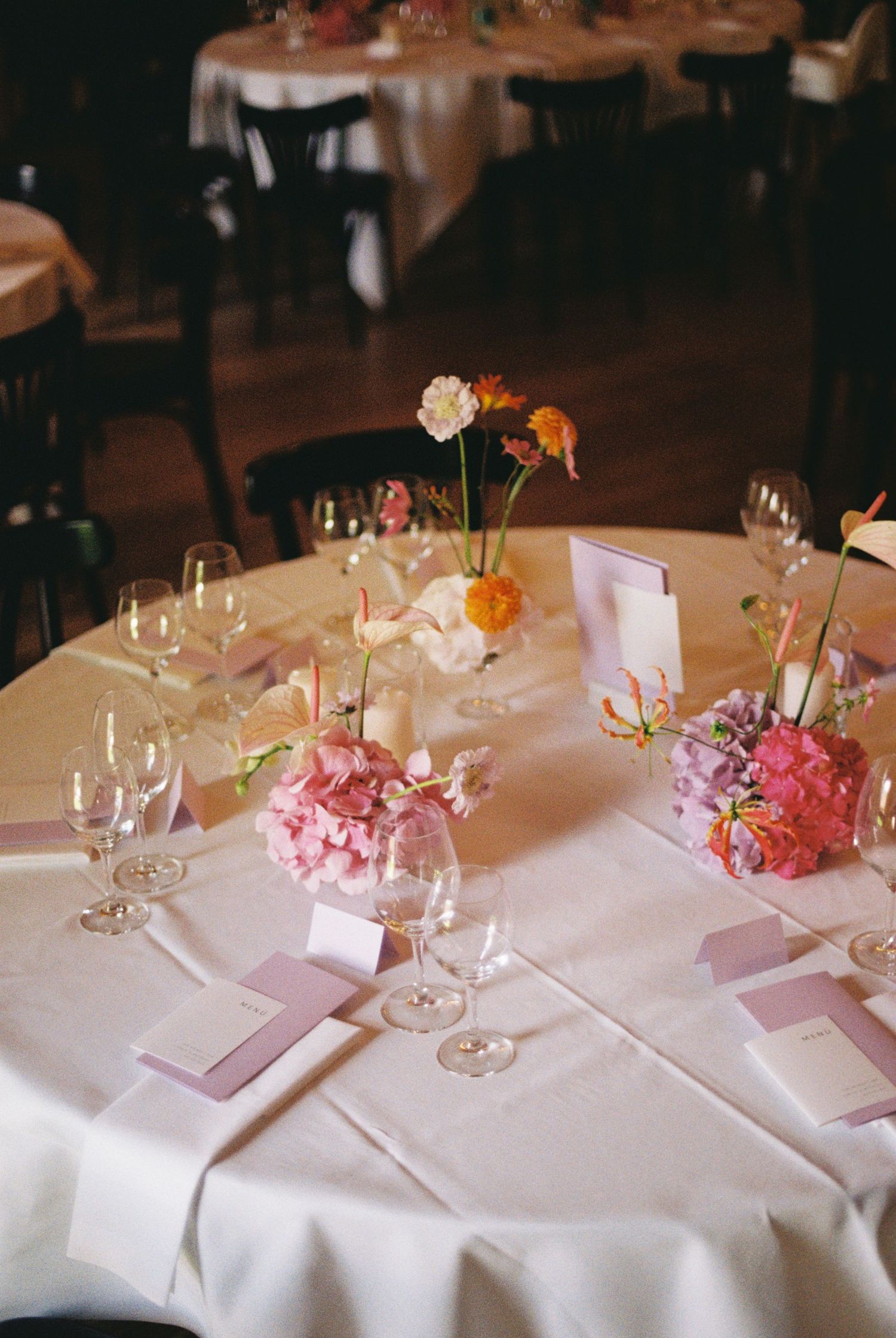 Elegant wedding table setting with pink floral centerpieces and wine glasses.