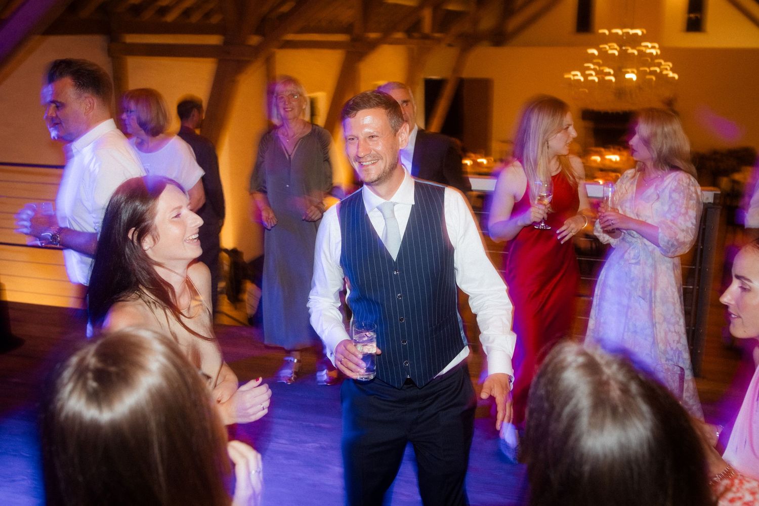 Wedding reception guests dancing and socializing beneath warm lighting.